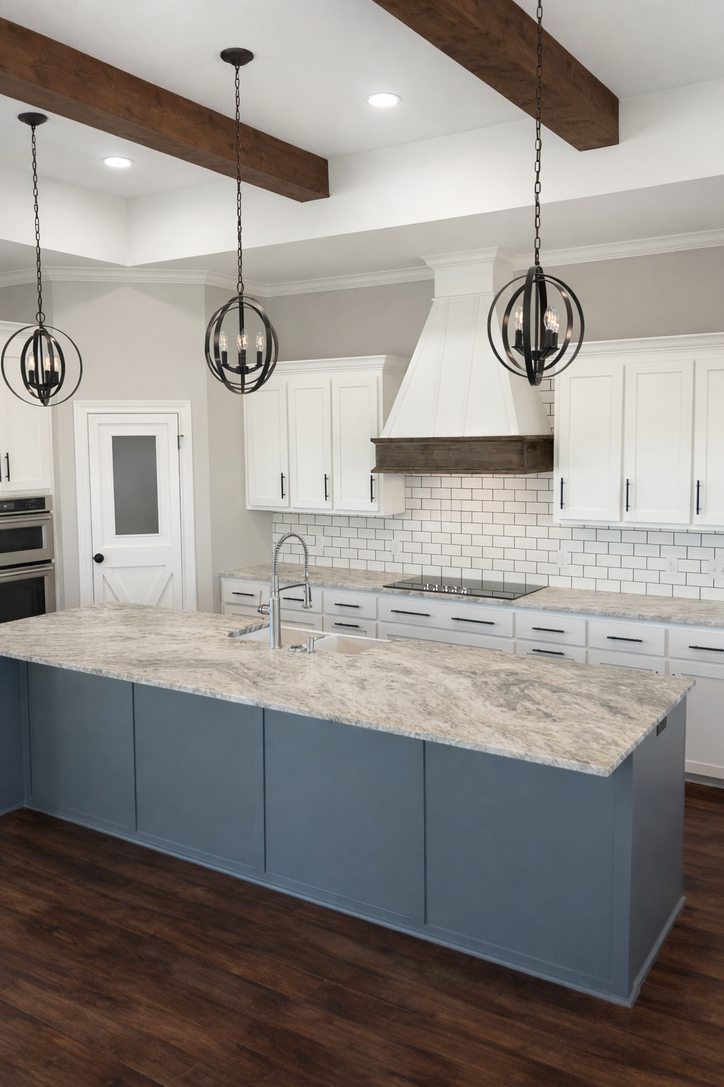 Modern kitchen with white cabinets, a marble countertop island, wooden beams on the ceiling, black pendant lights, white subway tile backsplash, and a white range hood.