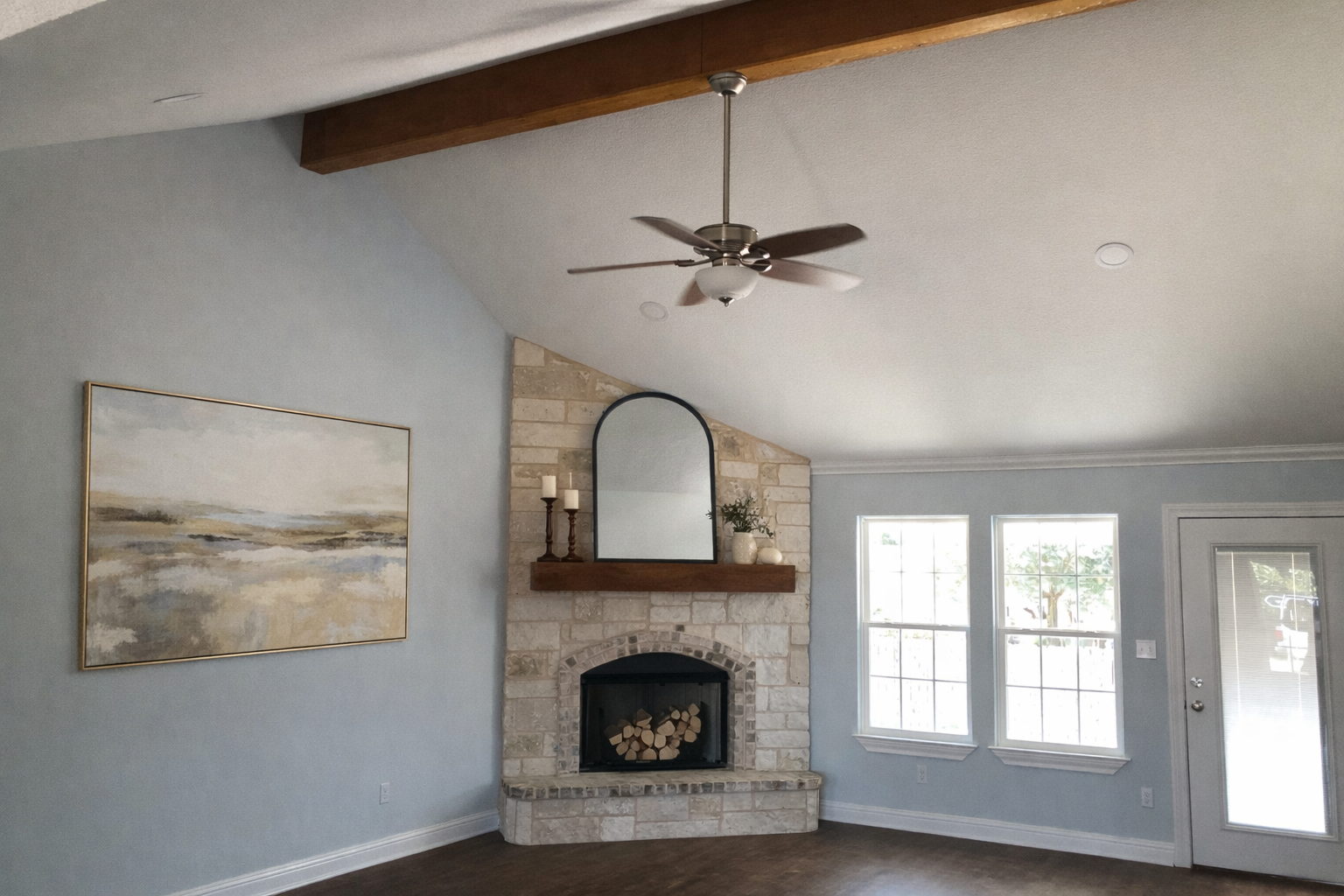 Living room with stone fireplace, two windows, and a door with a glass panel.