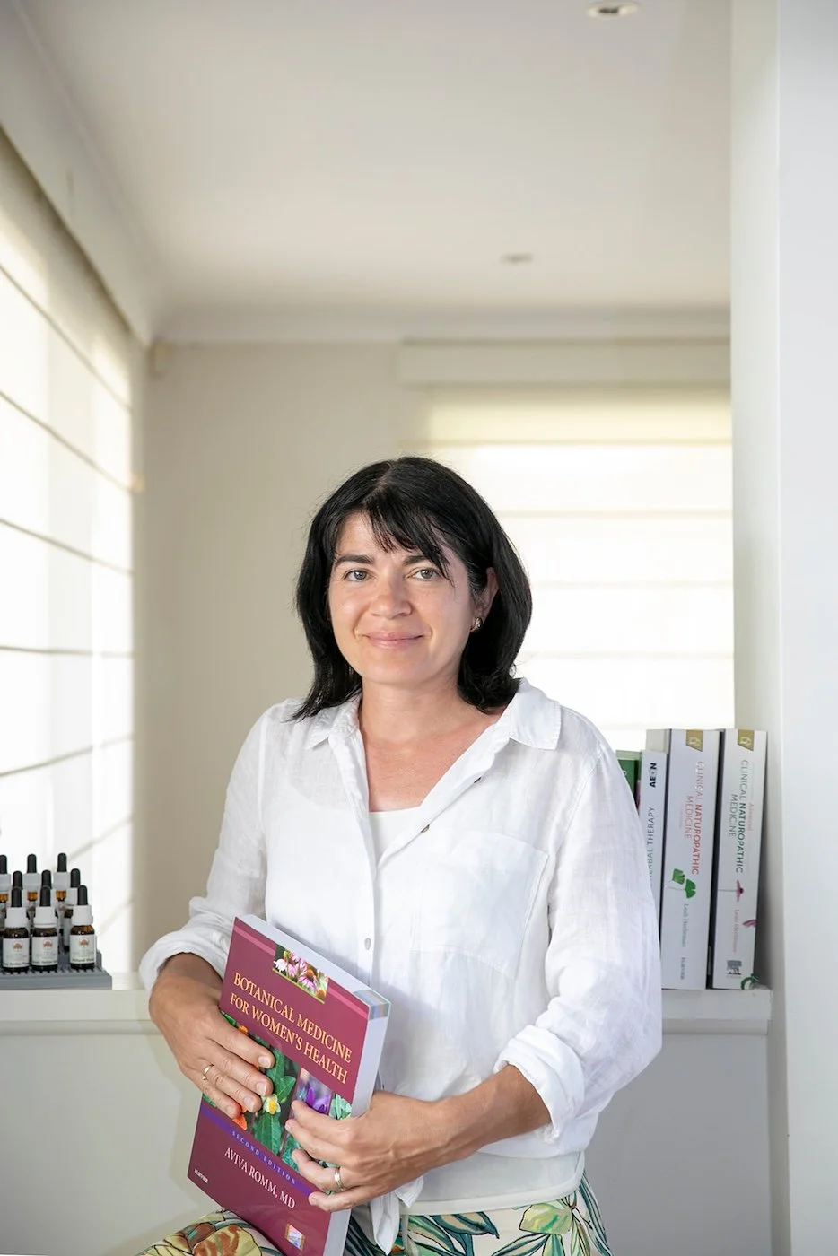 Anita Bordes, Practitioner at The Healing Meadow Naturopathy, Wellard WA, holding a guide on botanical medicine for women’s health and hormonal support.