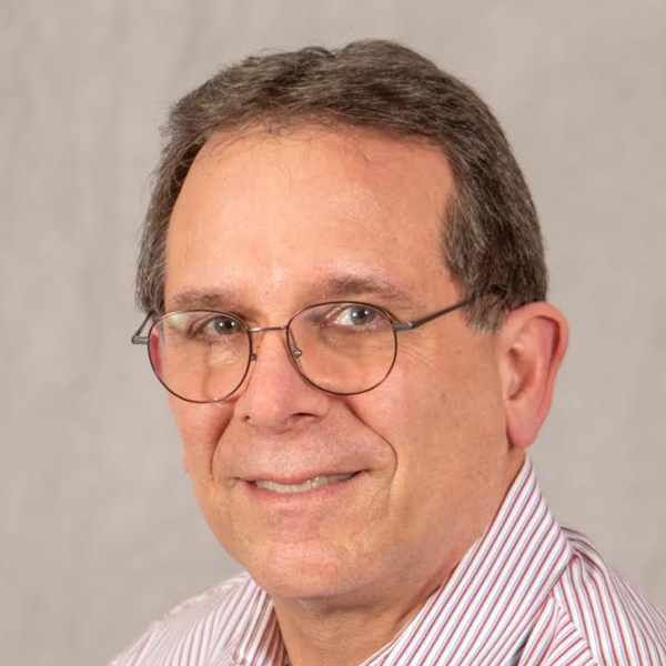 A middle-aged man with glasses, wearing a striped shirt, smiling against a neutral background.