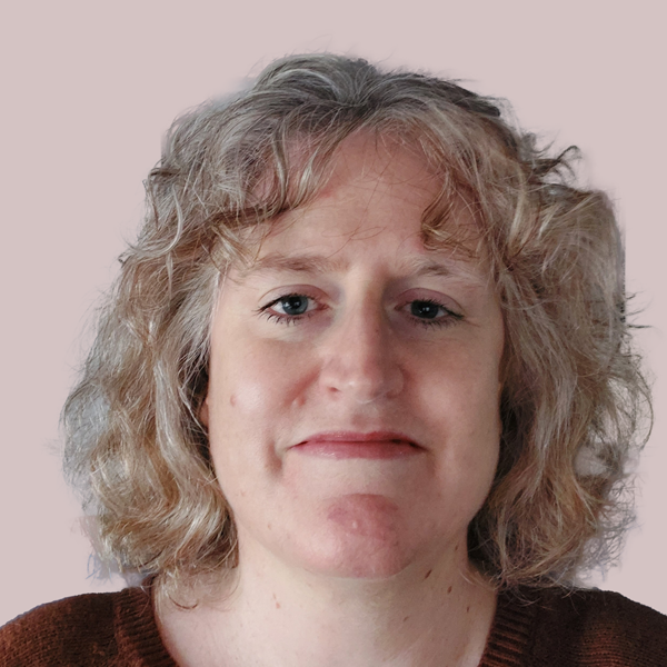 A woman with curly, shoulder-length blonde hair, wearing a dark sweater, against a light pink background.