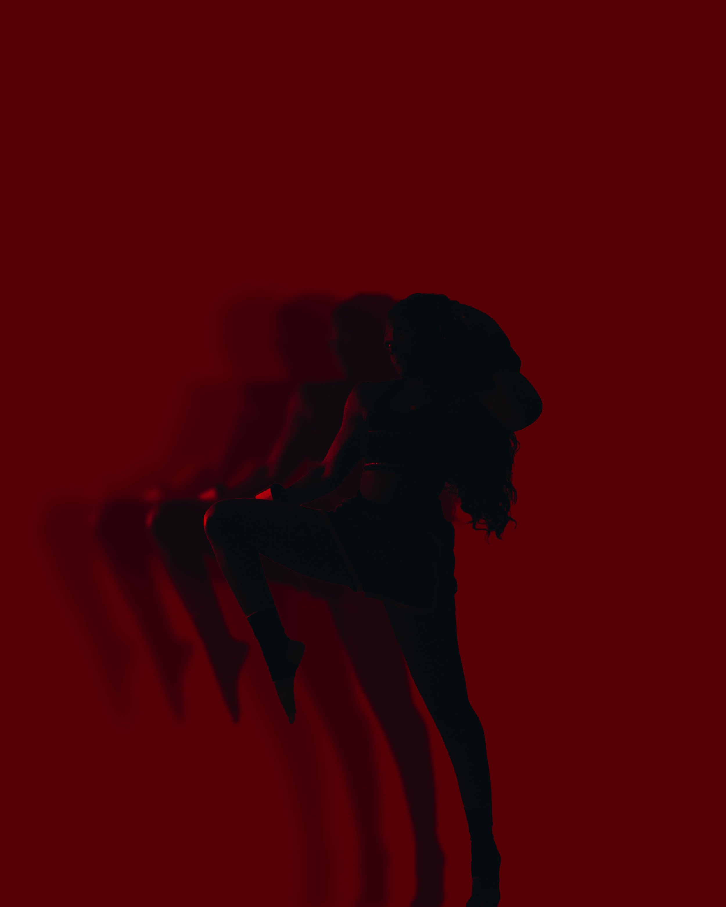 Silhouette of a woman with long hair posing with one leg up against a red gradient background with multiple shadowed copies of her in the background.