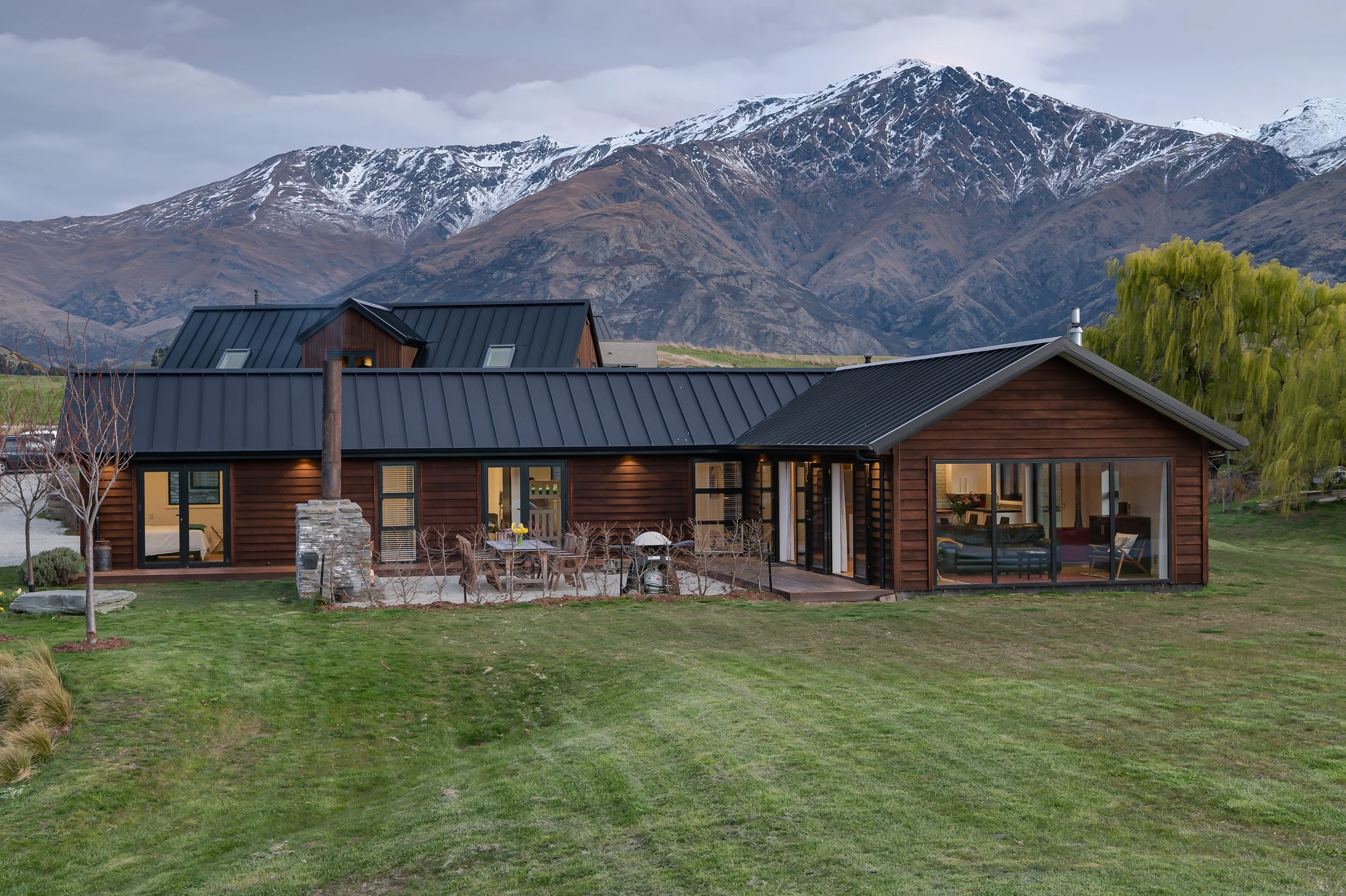 The front view of the timber clad home with the mountains in the background at a new home build in Threepwood by Diemarco Builders Queenstown.