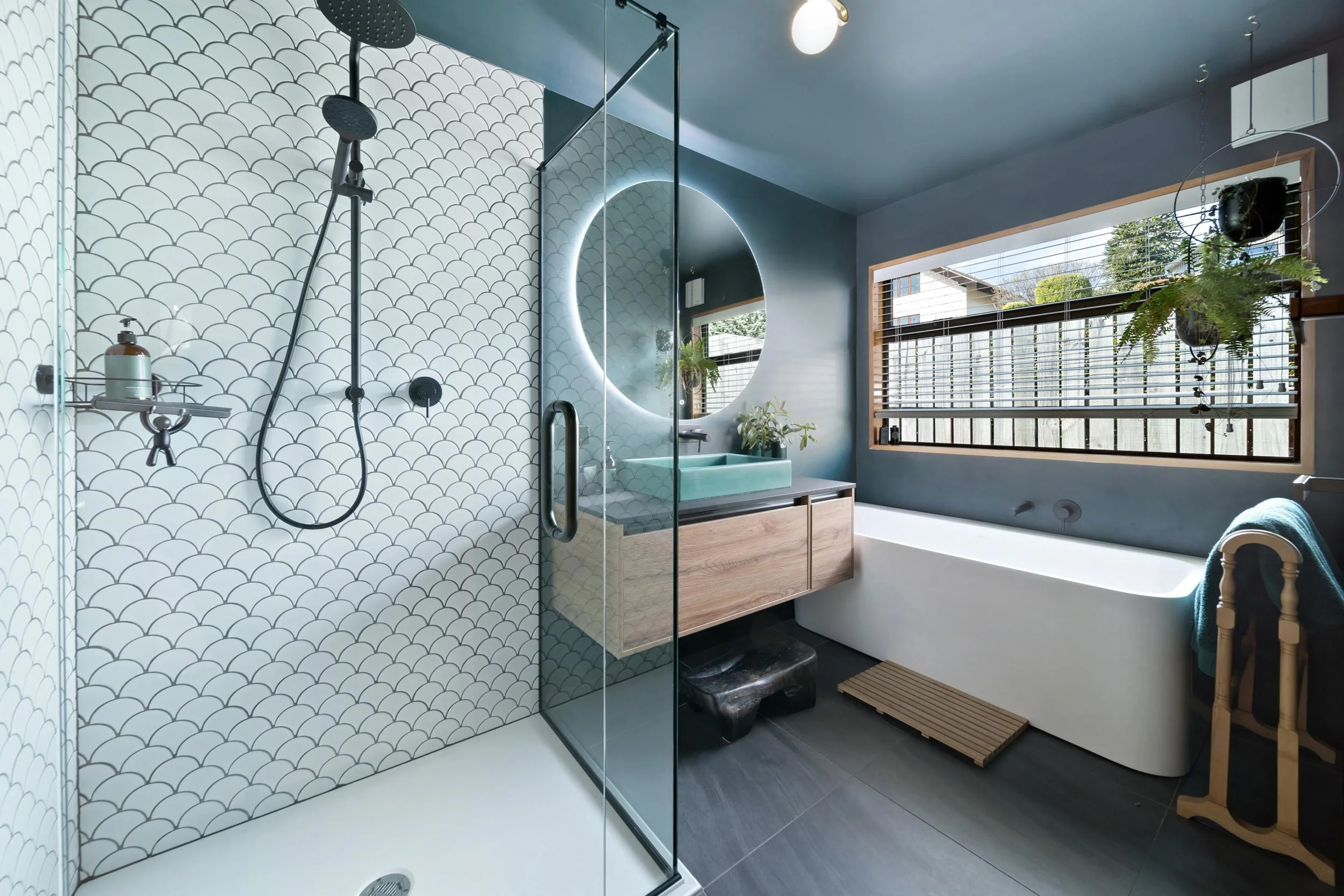 A stunning tiled and glass shower, led mirror over vanity and unique bathtub in the bathroom at a residential renovation in Kelvin Heights by Diemarco Builders Queenstown.