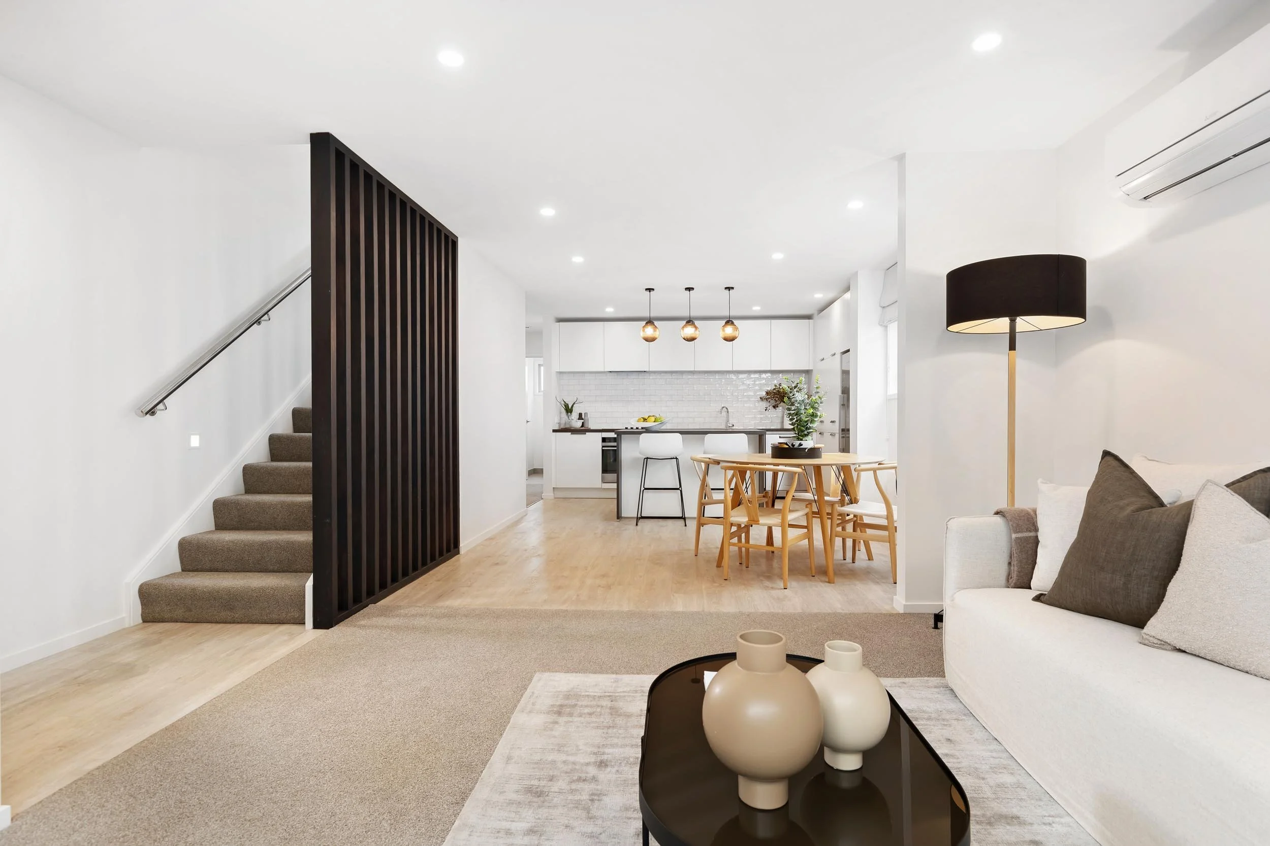 A newly renovated lounge and kitchen space with a screened stairway at a townhouse renovation project by Diemarco Builders Queenstown.