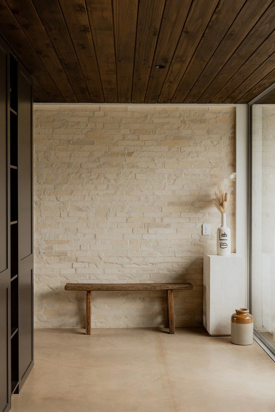 Dark timber clad ceiling with a feature brick wall in an architectural home built by Diemarco Builders Queenstown.
