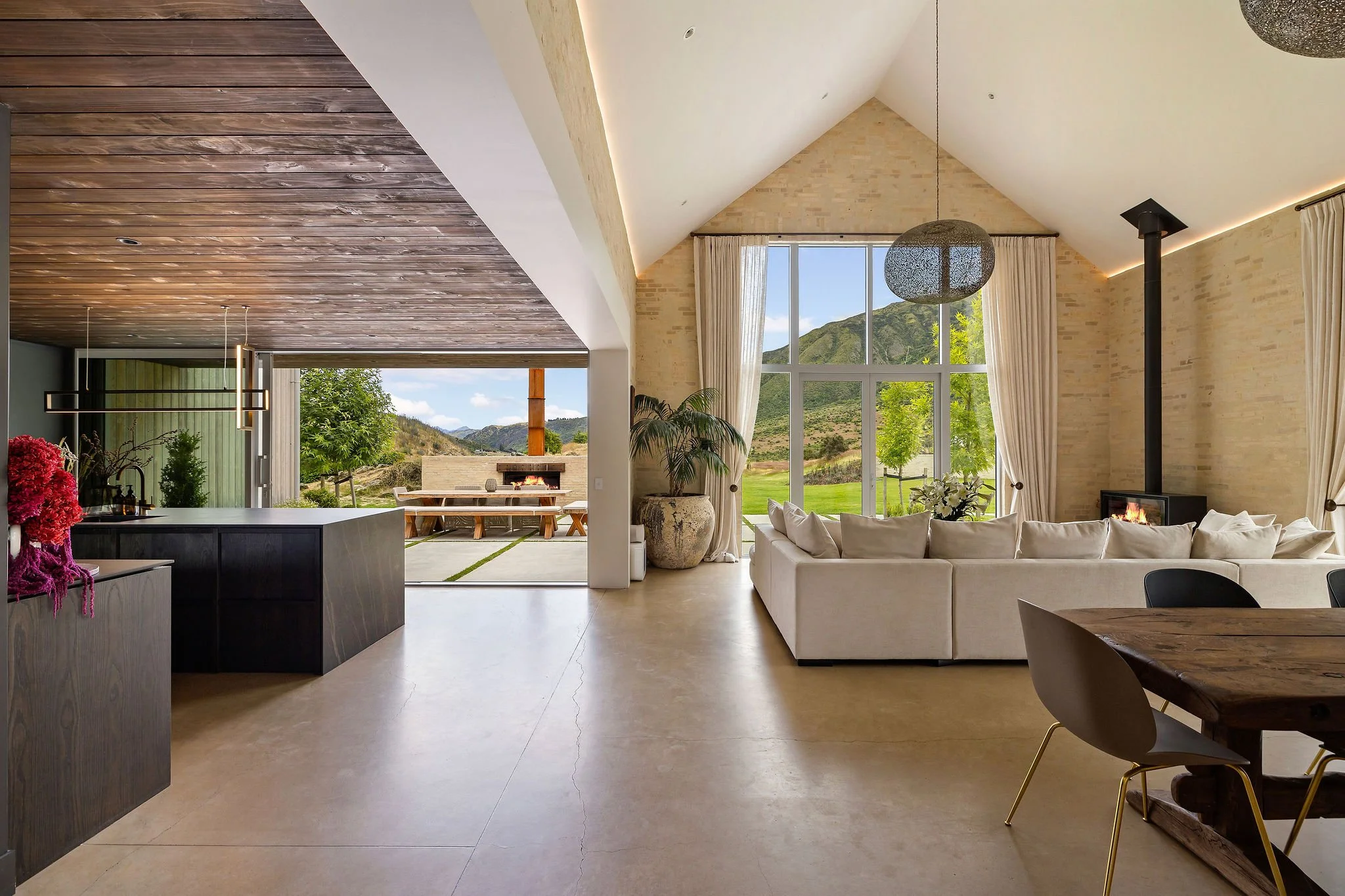 An open plan lounge area looking out feature windows at Peregine Ridge, a Gibbston Valley home built by Diemarco Builders Queenstown.