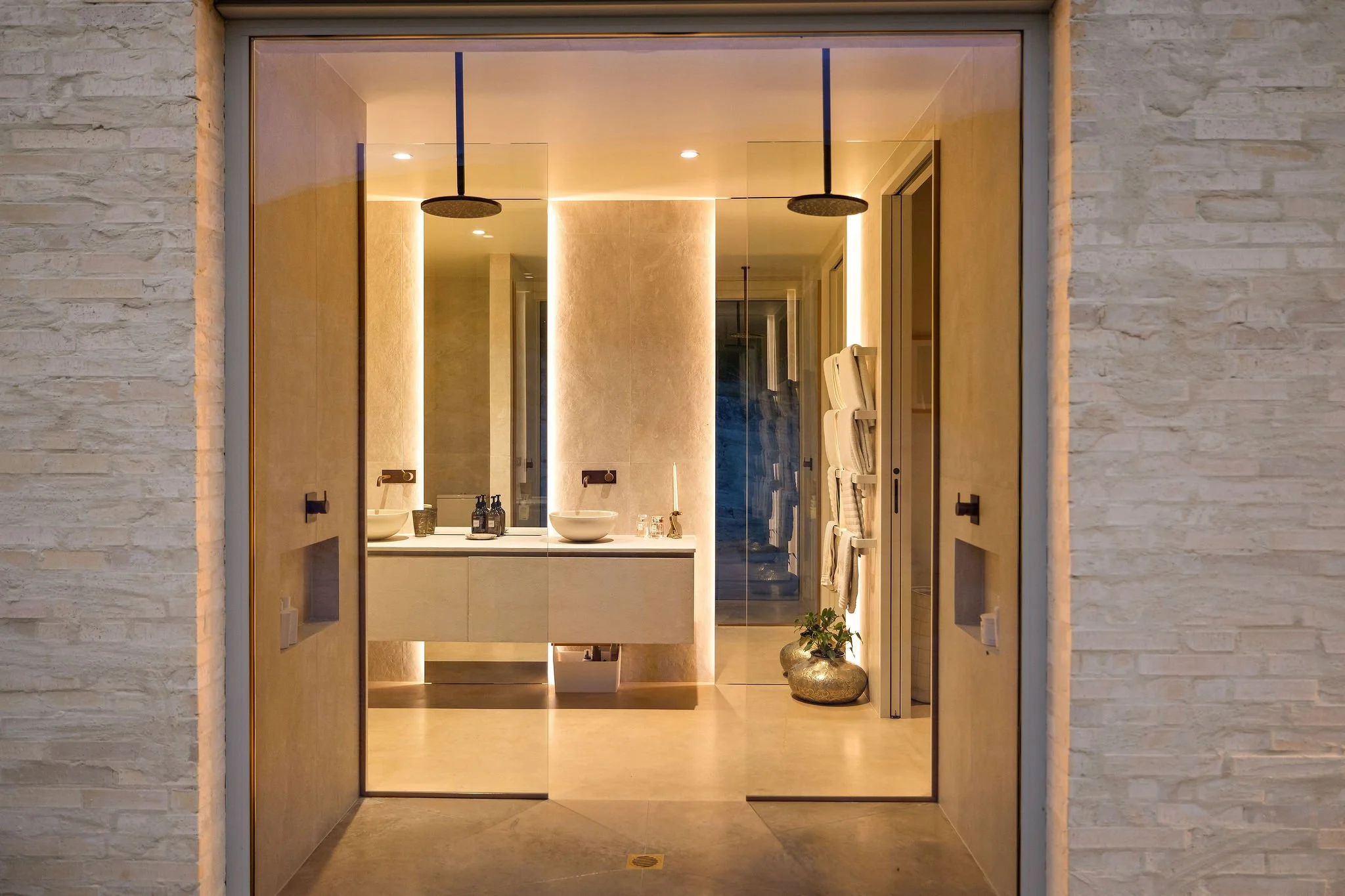 A look through to a feature bathroom with dual shower heads and accent lighting at Peregine Ridge, a Gibbston Valley home built by Diemarco Builders Queenstown.