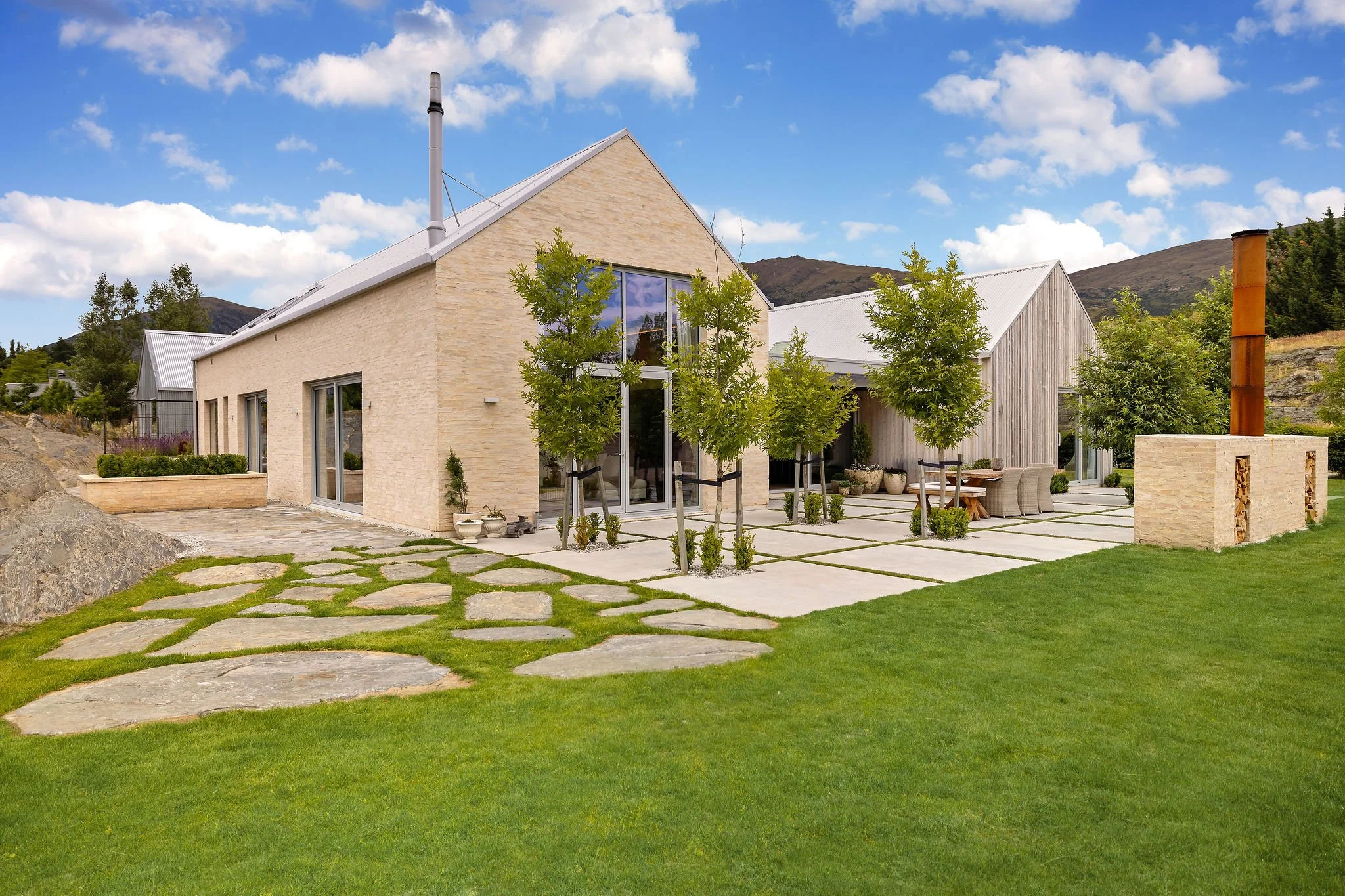 The front of the home with outdoor fireplace and dining at Peregine Ridge, a Gibbston Valley home built by Diemarco Builders Queenstown.