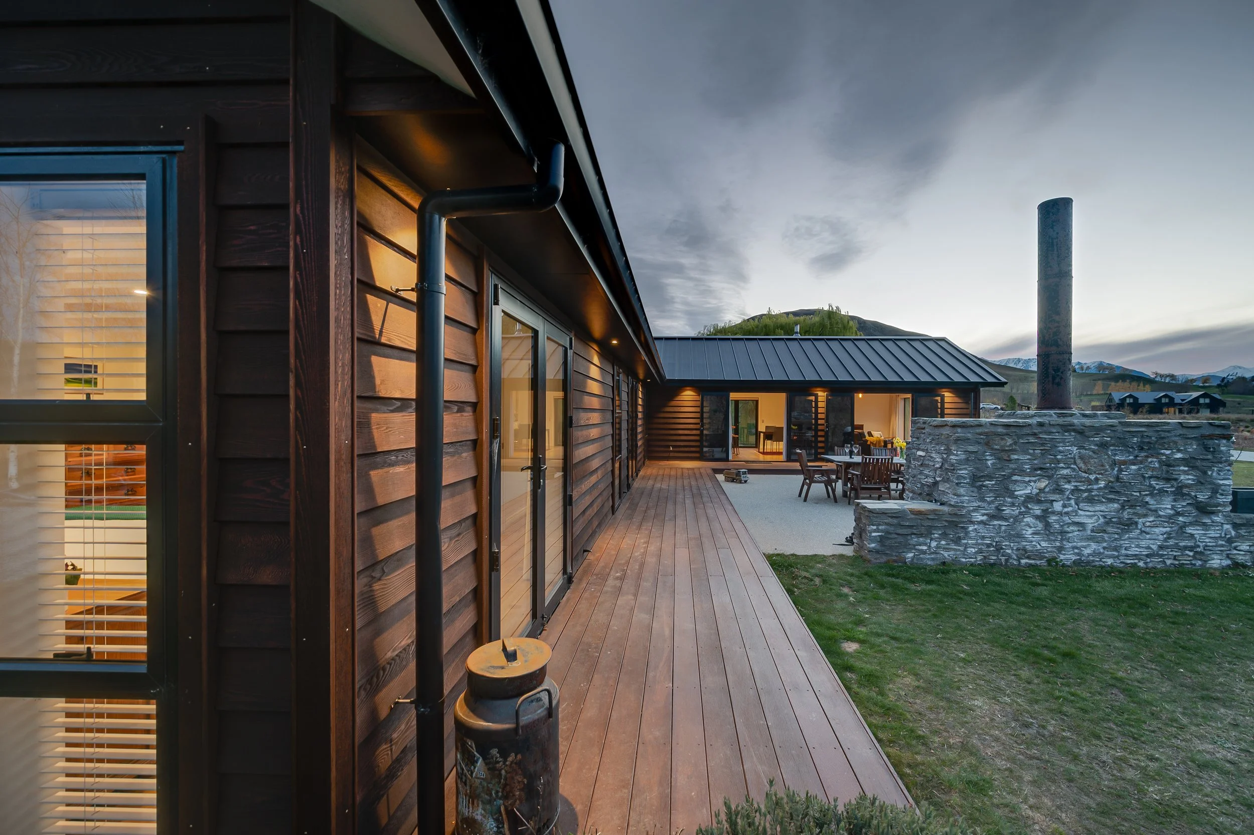 Wrap around decking, and timber exterior cladding looking towards an outdoor entertainment area of a new home build in Threepwood by Diemarco Builders Queenstown.