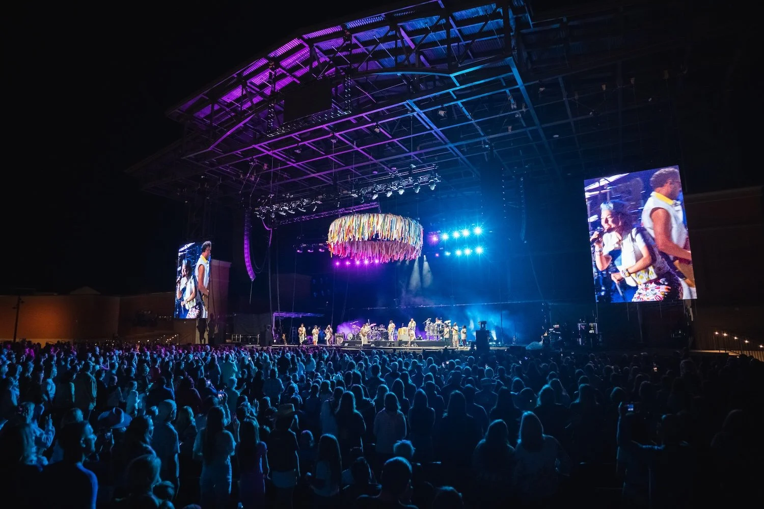 Outdoor concert at night with large crowd and colorful stage lighting in Kalispell, Montana in the Flathead Valley