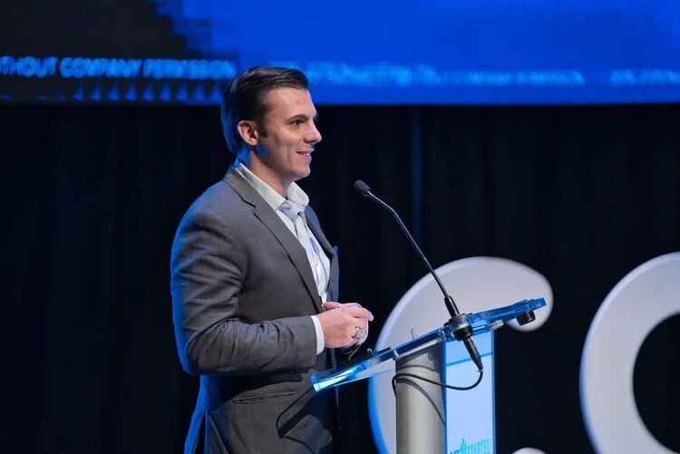 Man in a gray suit speaking at a podium in Kalispell, Montana in the Flathead Valley