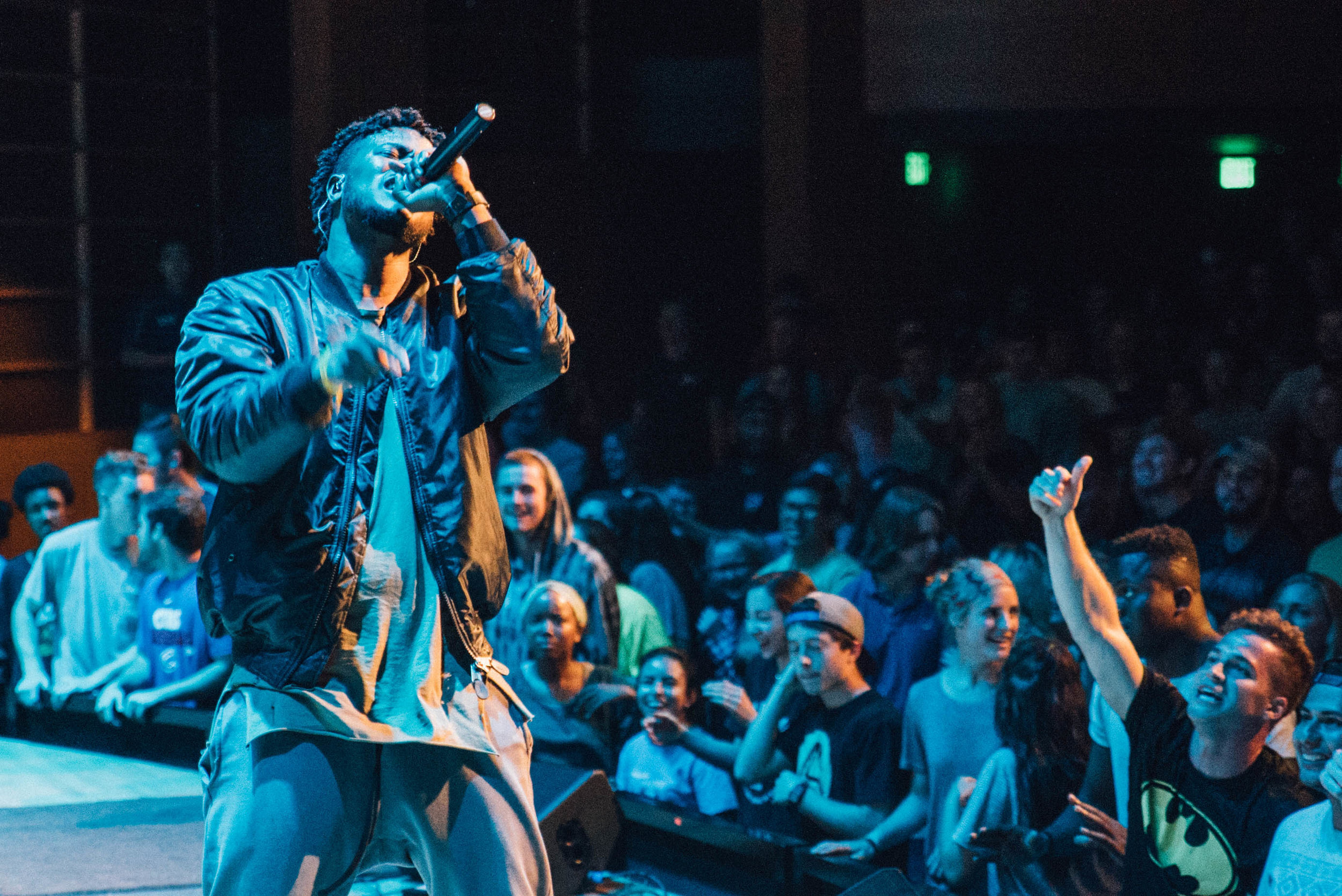 Performer singing on stage with microphone, lively crowd cheering in the background. Professional Event Photographer in Kalispell, Montana in the Flathead Valley.