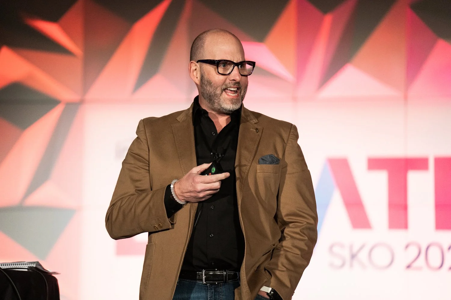 Man speaking at event, holding a clicker, wearing glasses, in Kalispell, Montana in the Flathead Valley
