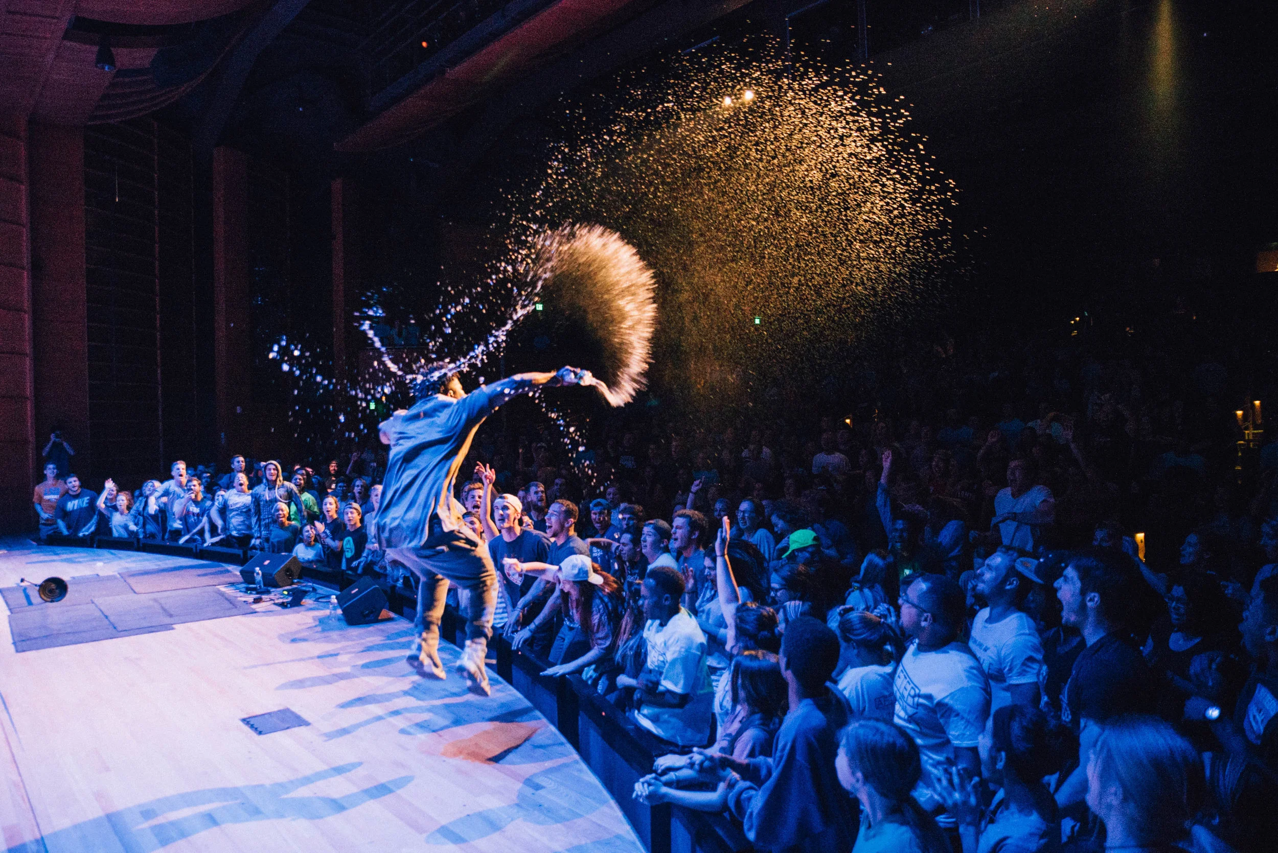 Performer on stage jumping and spraying liquid towards a lively audience in Kalispell, Montana in the Flathead Valley