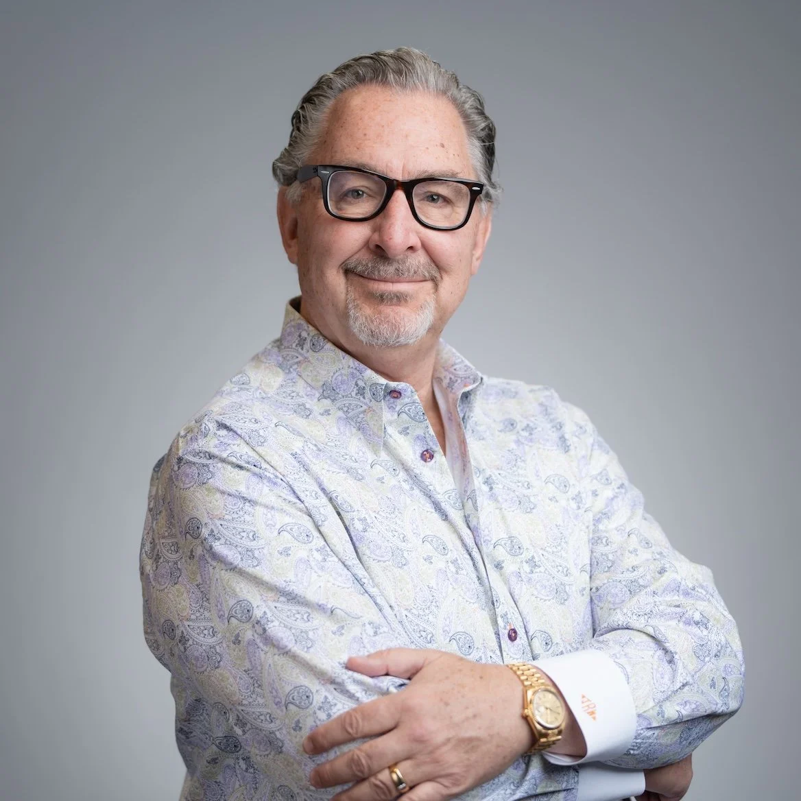 Man with glasses in a patterned shirt, arms crossed, smiling at the camera. Professional Headshot and Portrait Photographer in Kalispell, Montana in the Flathead Valley.
