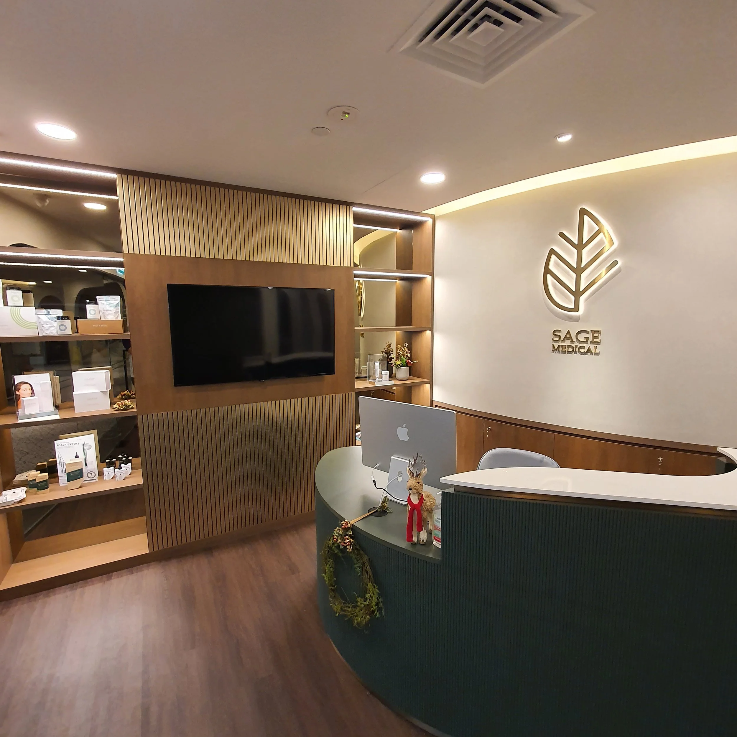 Reception area with a wooden and white theme, featuring a logo on the wall, a curved desk, and shelves with products.