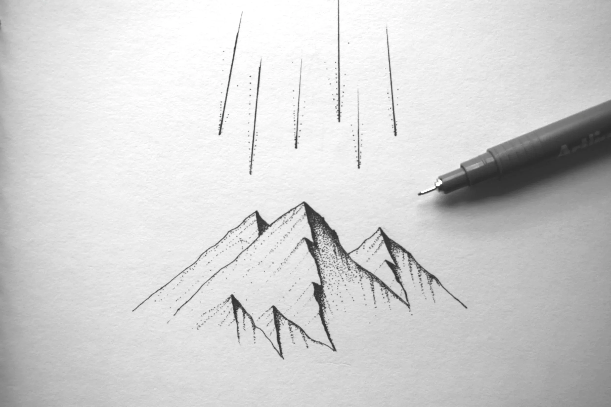 Minimal mountain sketch in black ink with drawing pen on white paper.