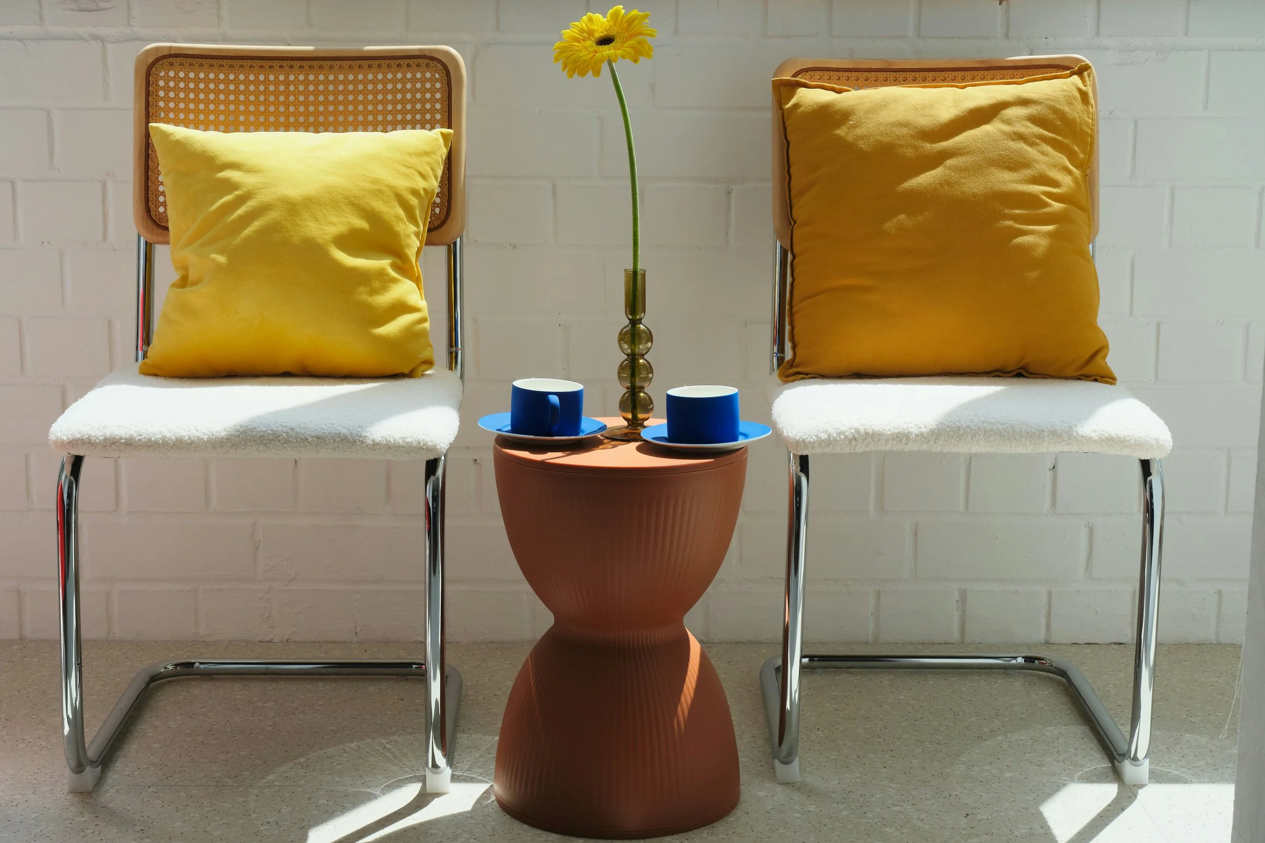 Two chairs with yellow pillows and a small table arranged for a therapy or counseling session