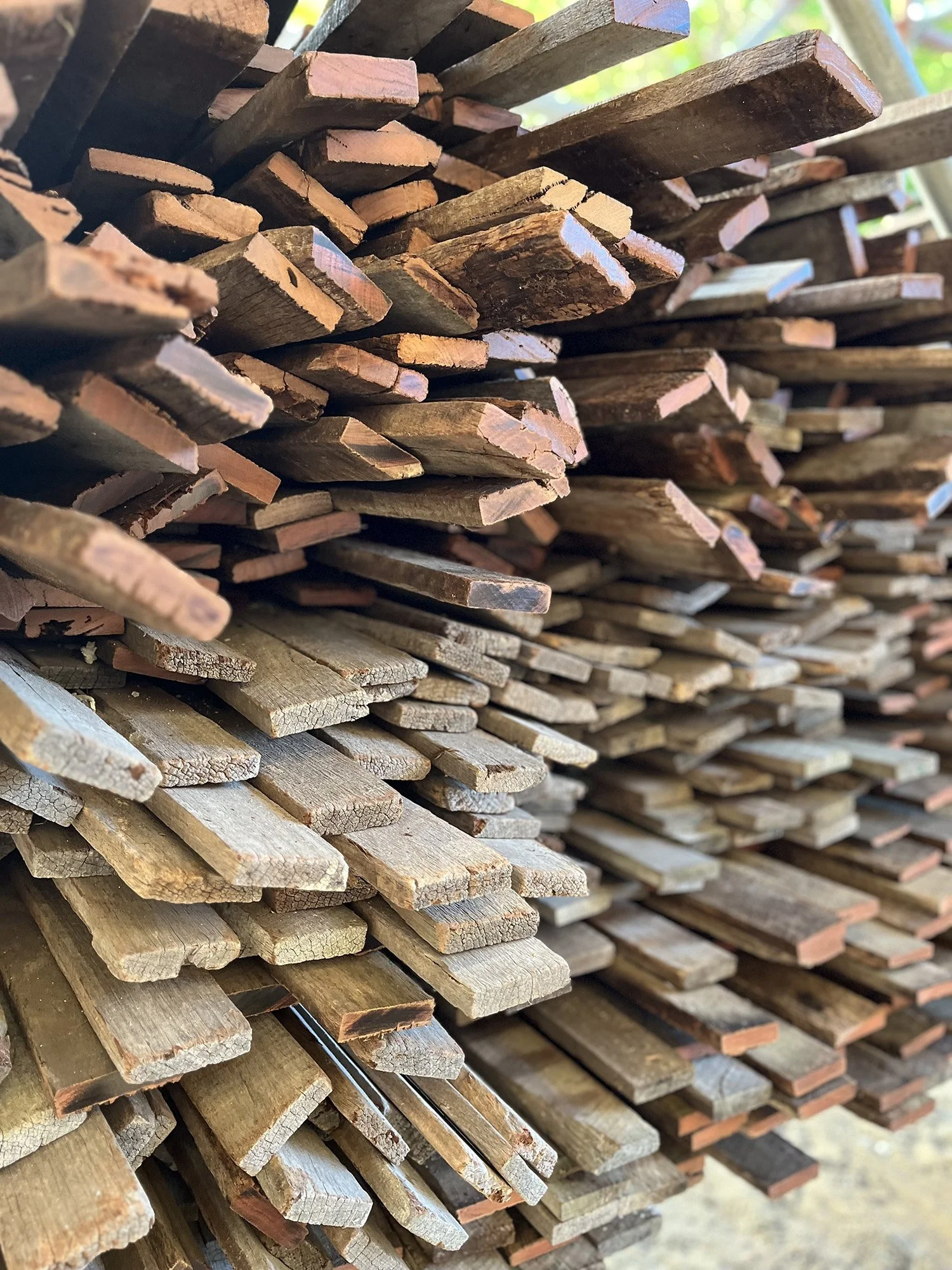 Stacked pile of wooden planks and scrap wood in an outdoor setting.