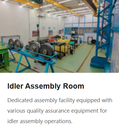 Inside an idler assembly room with various assembly stations, large rollers, workbenches, and machinery for quality assurance in idler assembly operations.