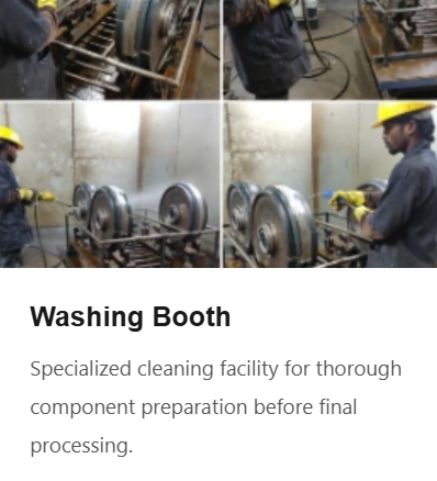 Two workers in yellow helmets and safety gear working at a cleaning booth with large metal wheels, using industrial equipment for component cleaning.
