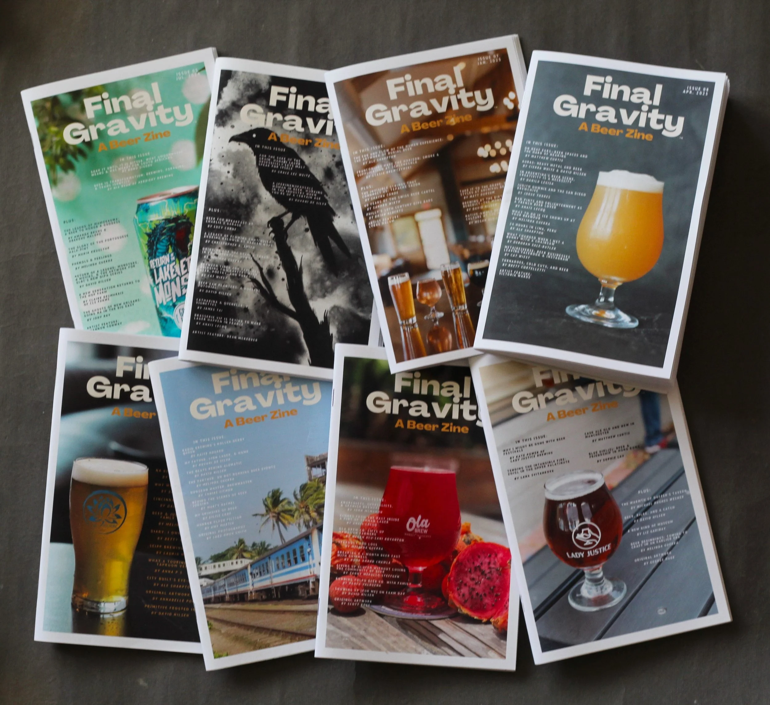 Photo of the first eight issues of Final Gravity, A Beer Zine, lying beside each other on a gray surface