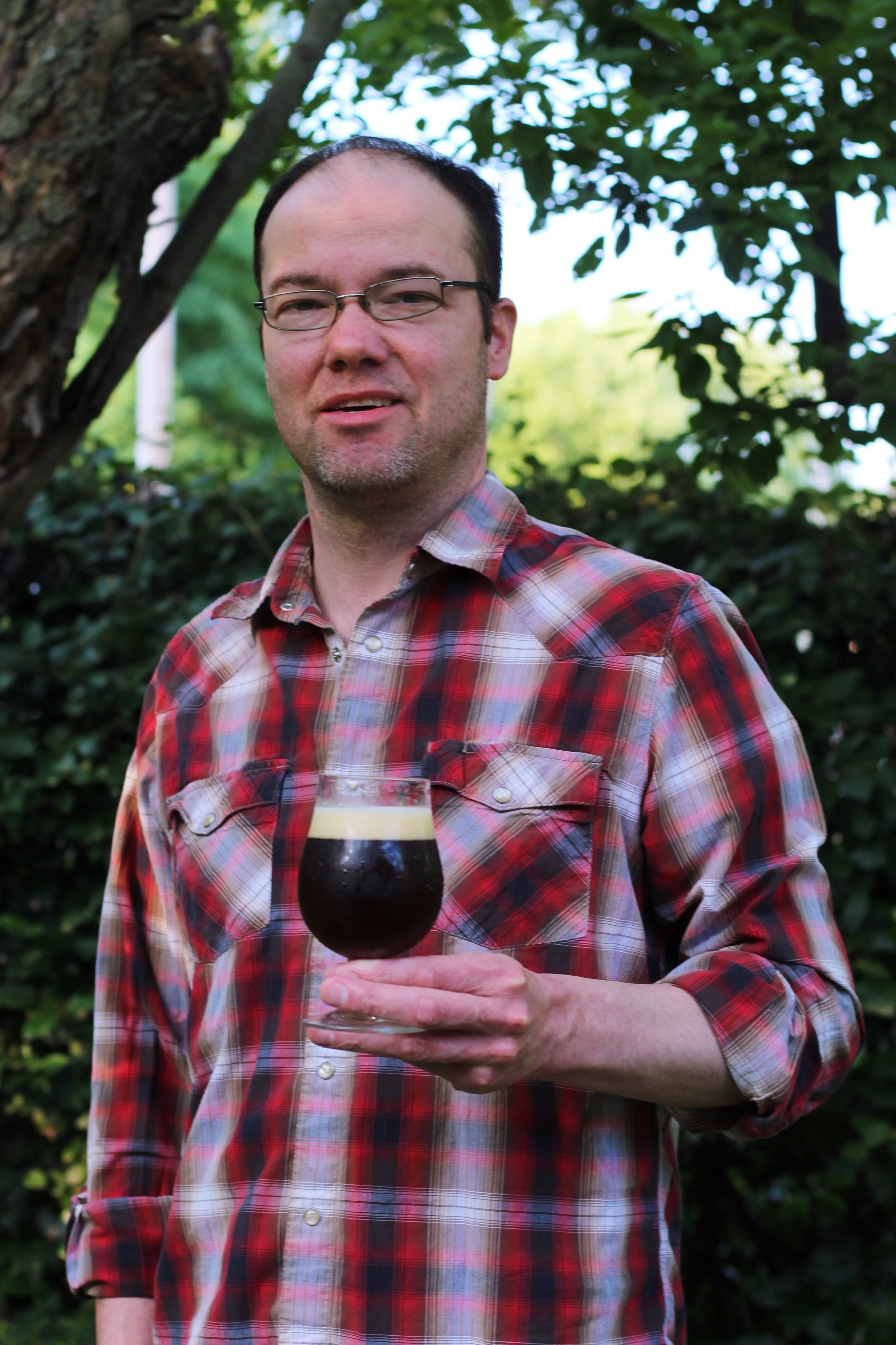 Photo of David Nilsen holding a beer glass outdoors, smiling at the camera