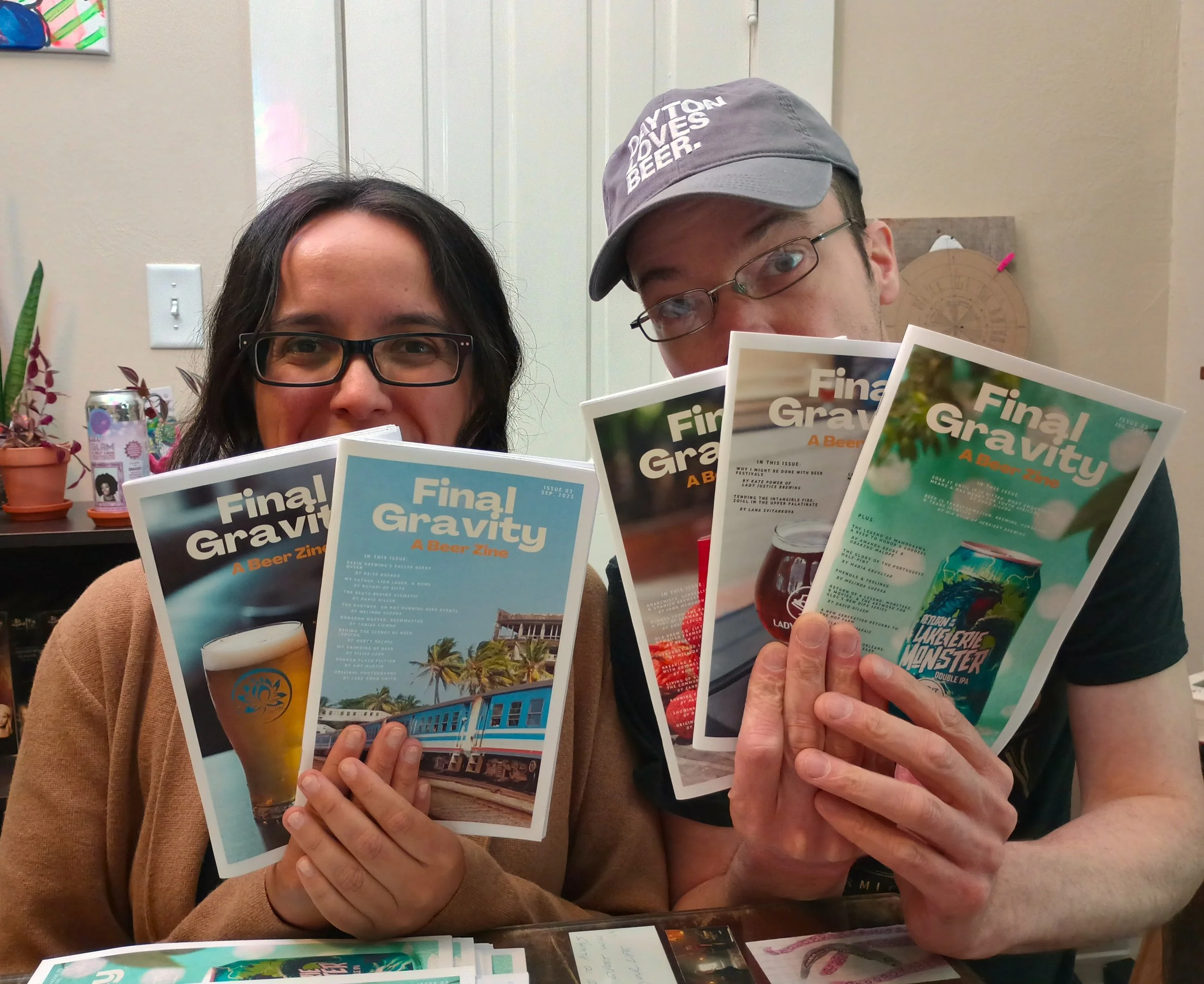 Photo of David Nilsen and Melinda Guerra holding copies of Final Gravity zine in front of faces, with only their eyes visible.