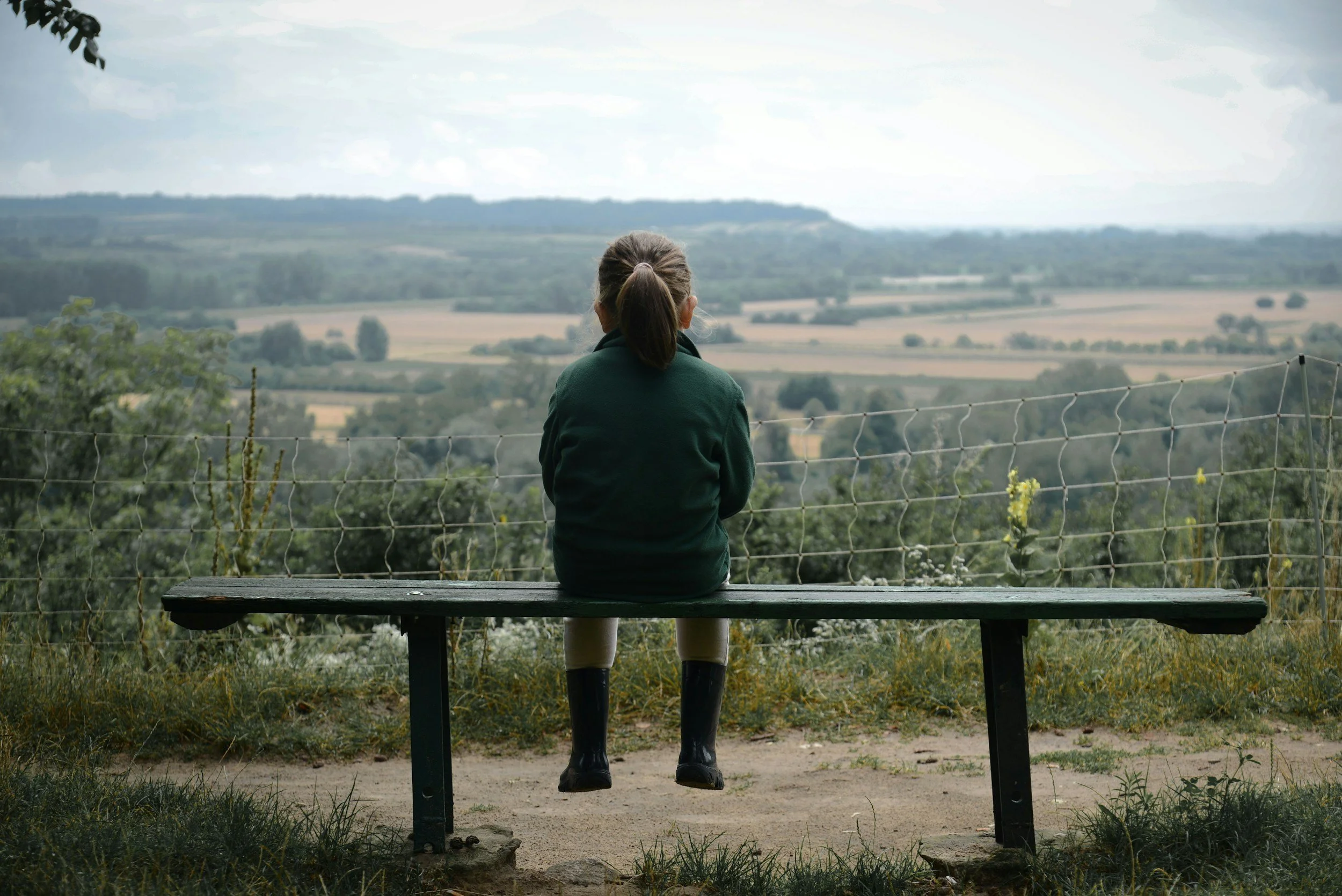 Child sitting alone on a bench overlooking an open landscape + Inner Child Messenger + emotional safety and gentleness