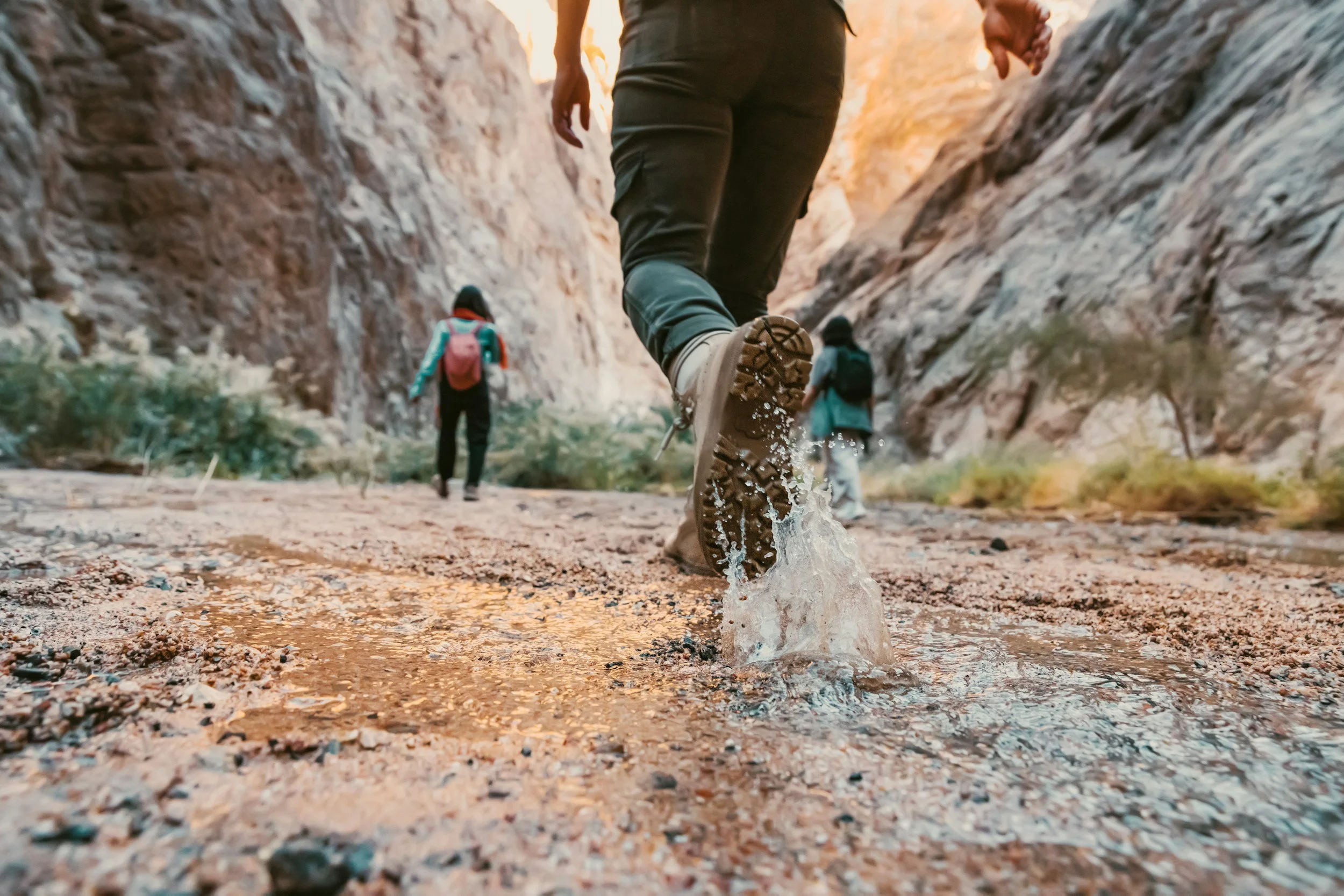 Person stepping forward through shallow water on a canyon trail + Action Messenger + aligned forward momentum