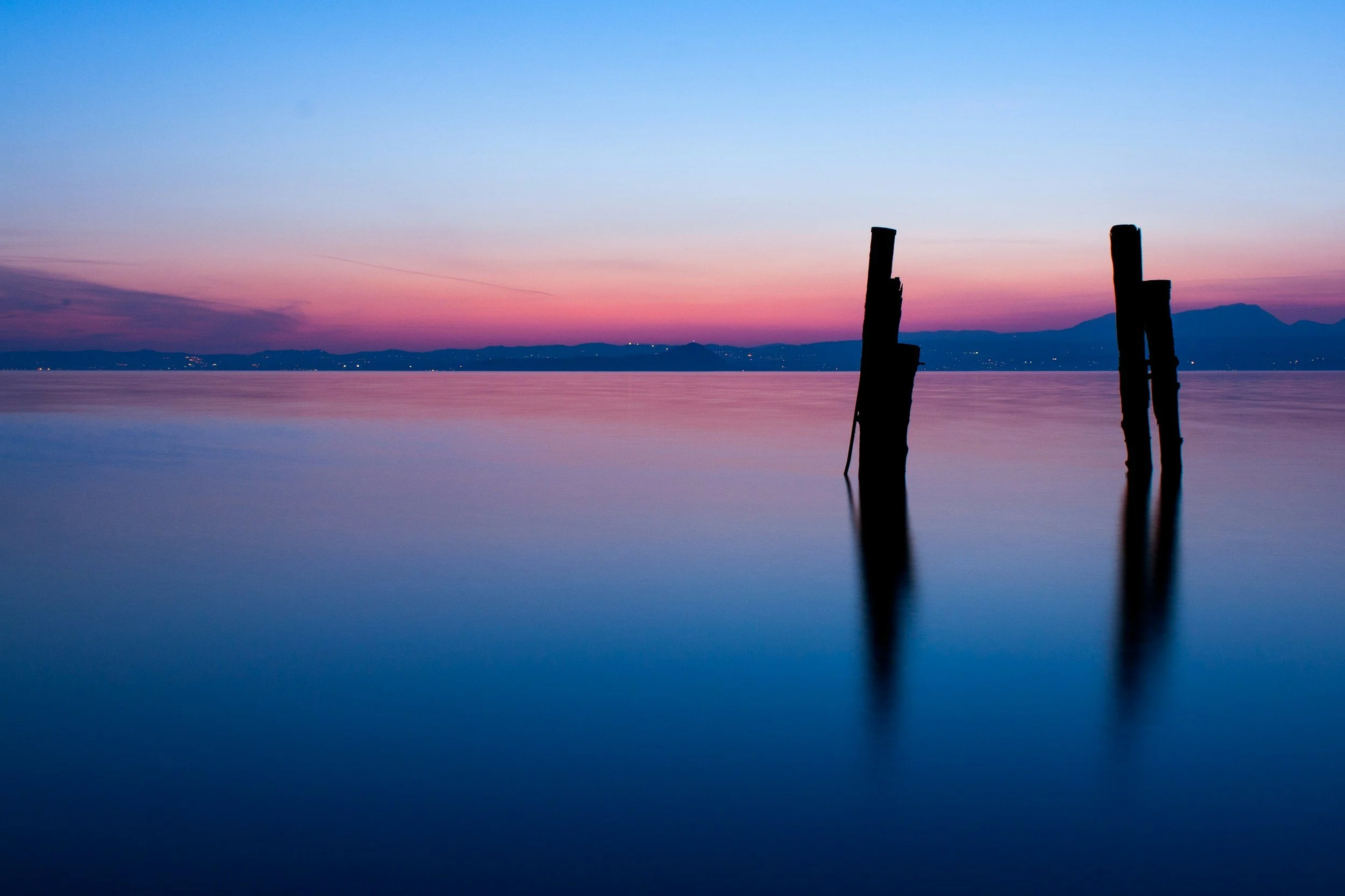 Calm water at dawn, perfectly still, suggesting acceptance and rest. Peace guide.