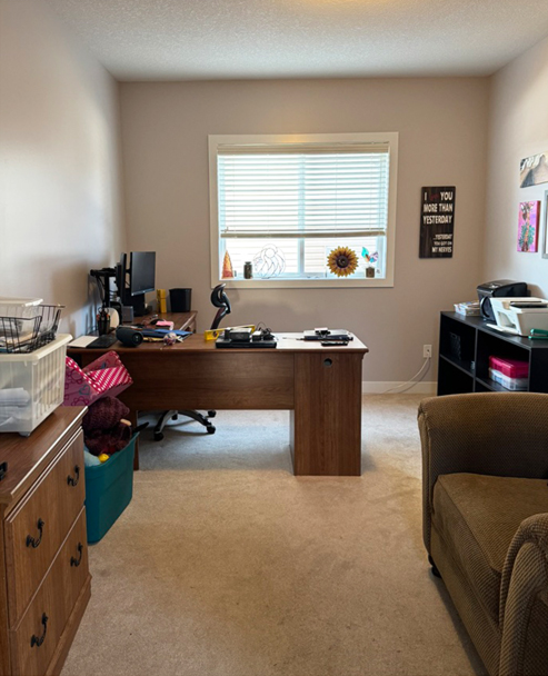 Organized home office in Calgary with a clear desk, tidy shelving, and open floor space after professional organizing.