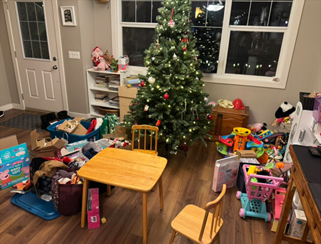Cluttered Calgary living room before organizing, with boxes, bins, and toys piled around a Christmas tree.