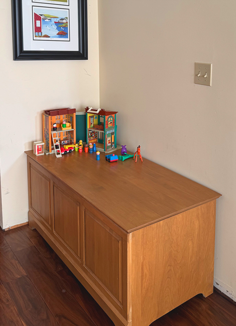 Organized wooden toy chest in Calgary home with a few neatly arranged toys after decluttering.