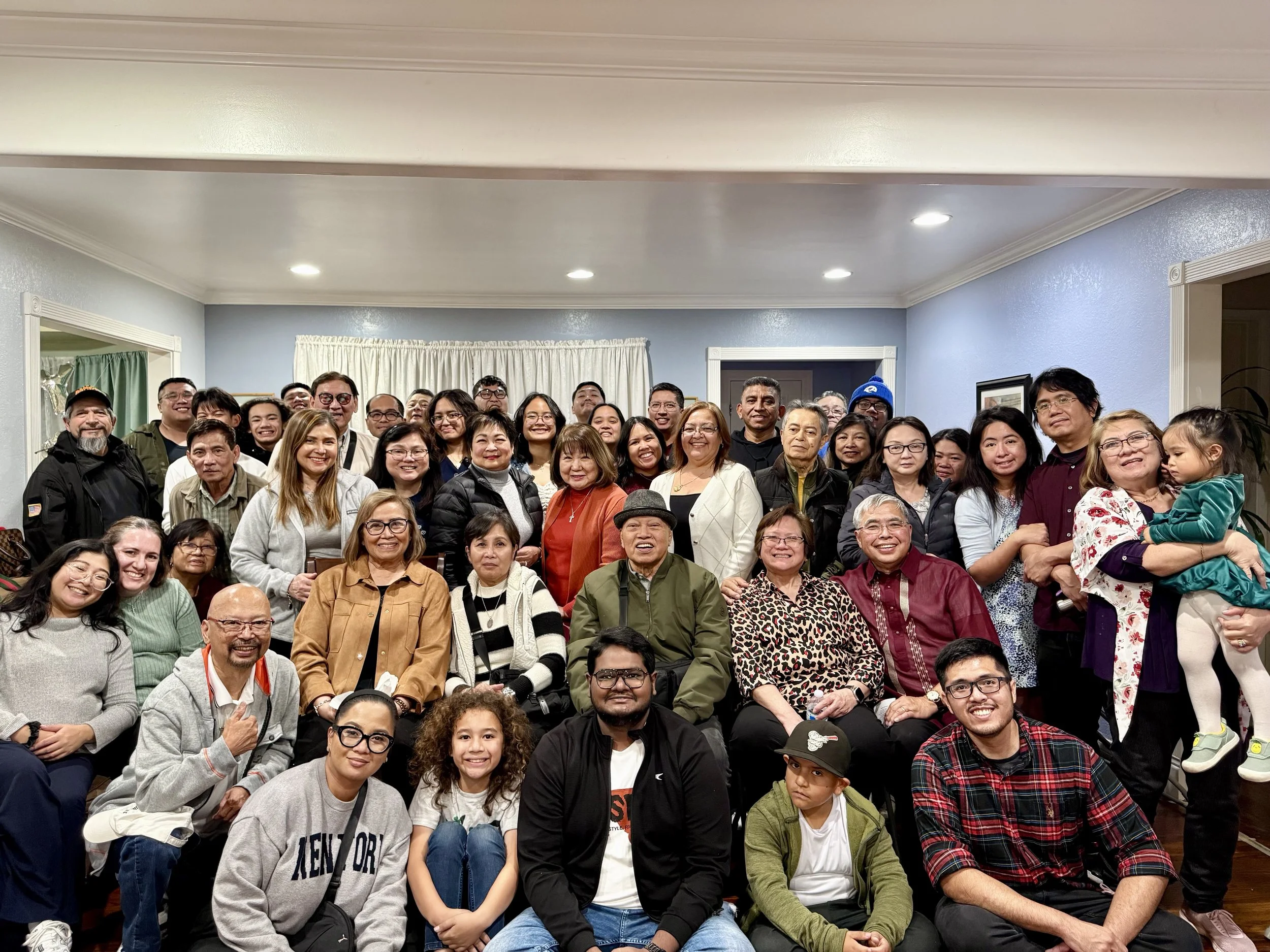 A large group of people posing together in an indoor setting, smiling for a group photo.