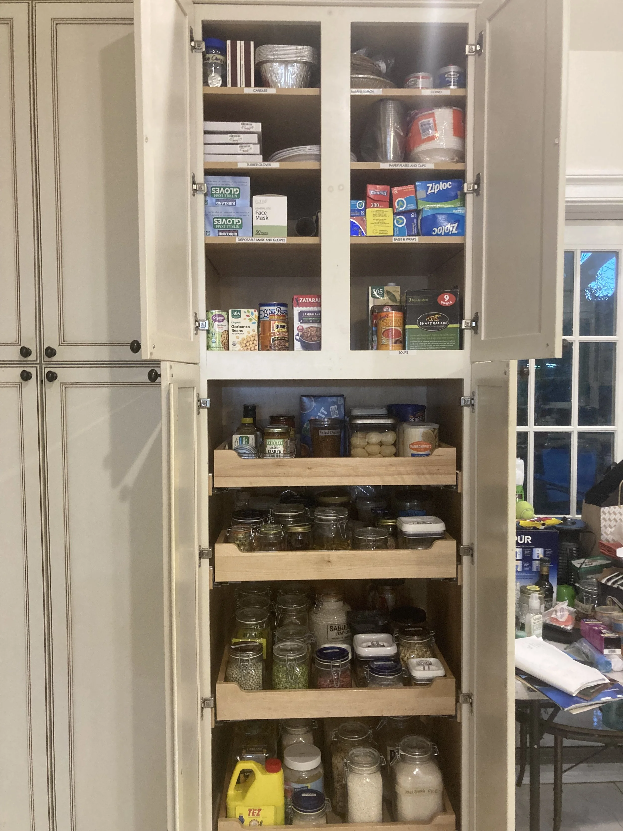 Open kitchen pantry with shelves of canned foods, jars, spices, and storage containers.