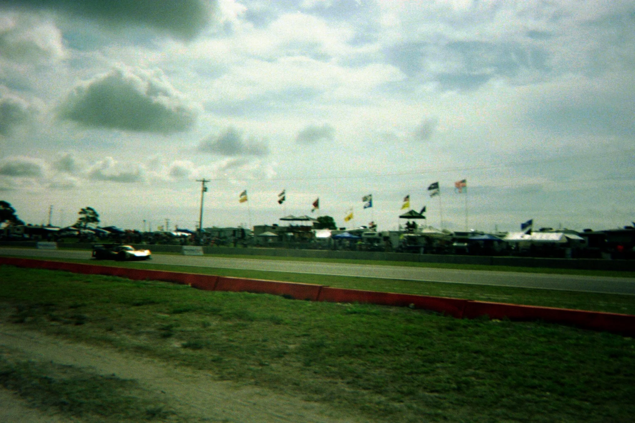 Race track with a race car and flags in the background, possibly at a motorsport event