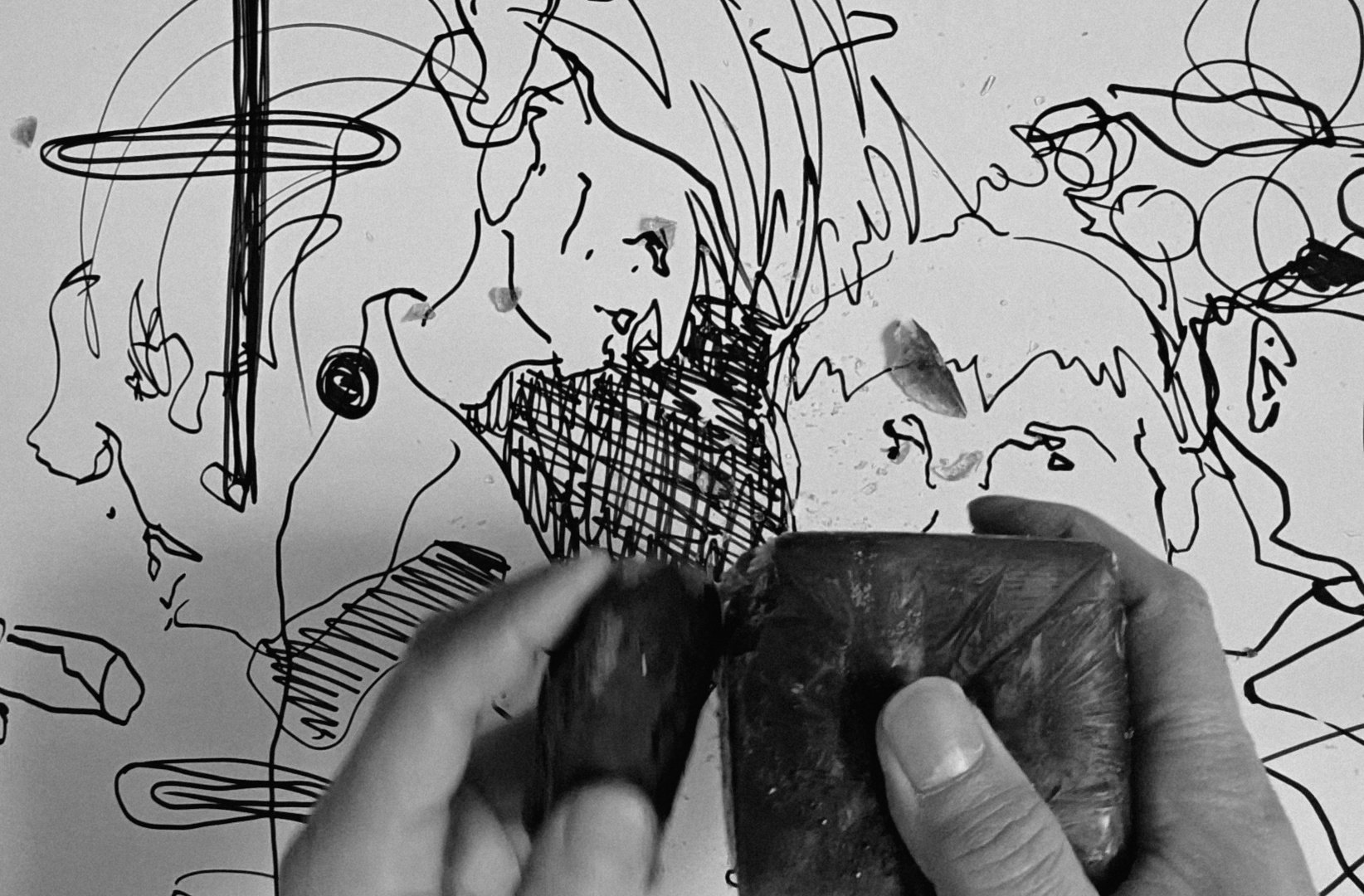 Person drawing a stylized portrait of a woman on a whiteboard with a black marker. The drawing is abstract and cartoonish.