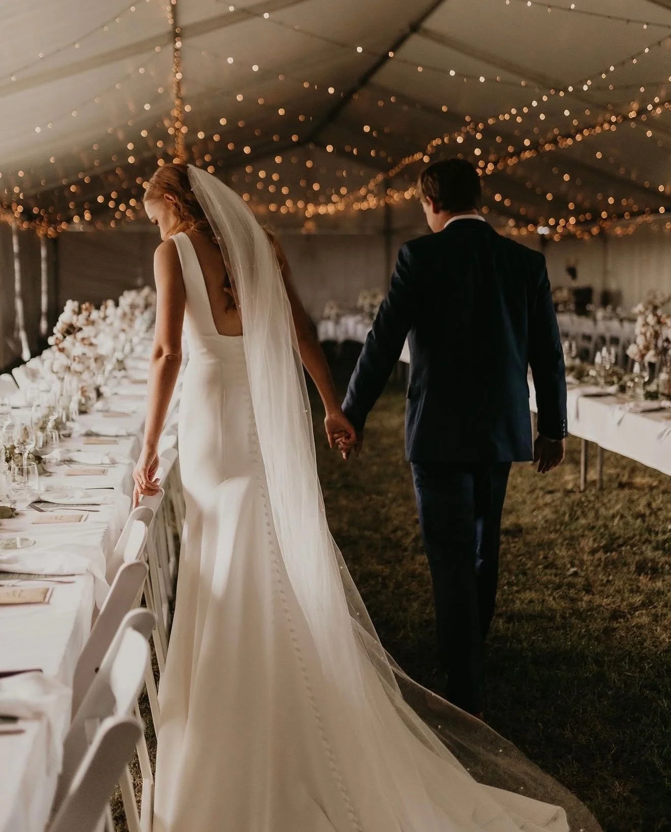 Bride and groom walking hand in hand for their first look at reception decor set up by Brisbane day-of coordinator