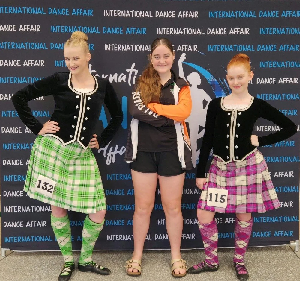 Highland dancers posing in front of a step and repeat