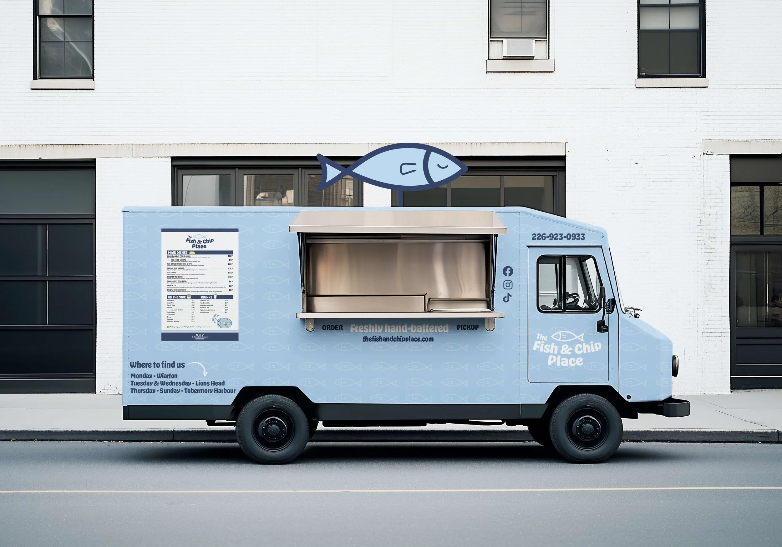 Light blue Fish & Chip Place food truck parked along a street, featuring a rooftop fish graphic, a side serving window, a detailed printed menu of fish‑and‑chip offerings, weekly location schedule, contact information, and social media icons.