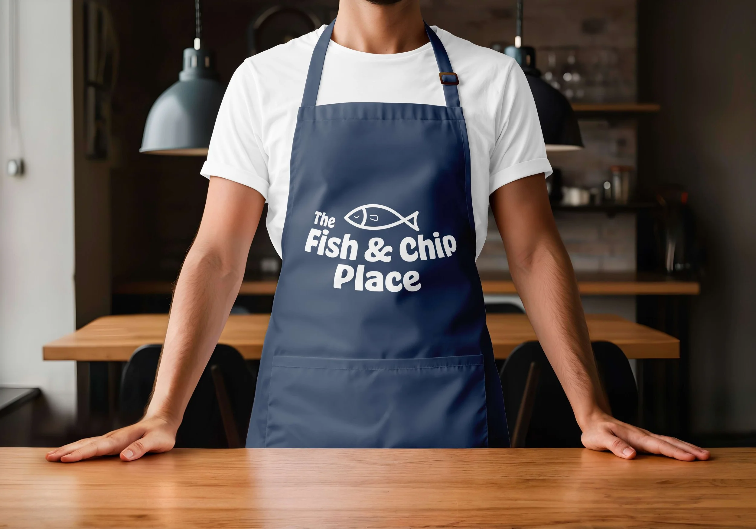 Restaurant chef wearing a dark blue apron featuring white variation of restaurant logo.