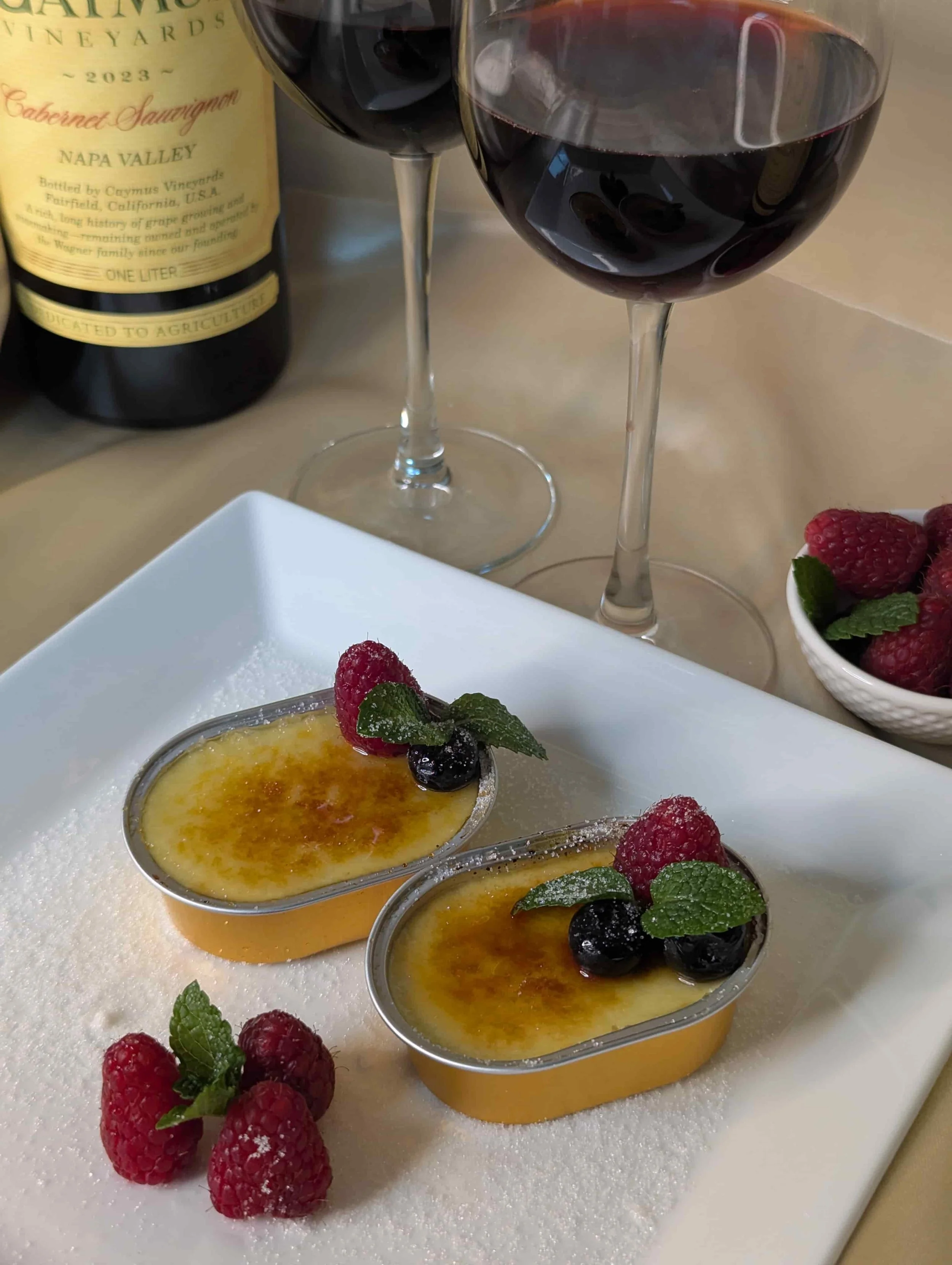 Gourmet crème brûlée dessert topped with berries served with red wine