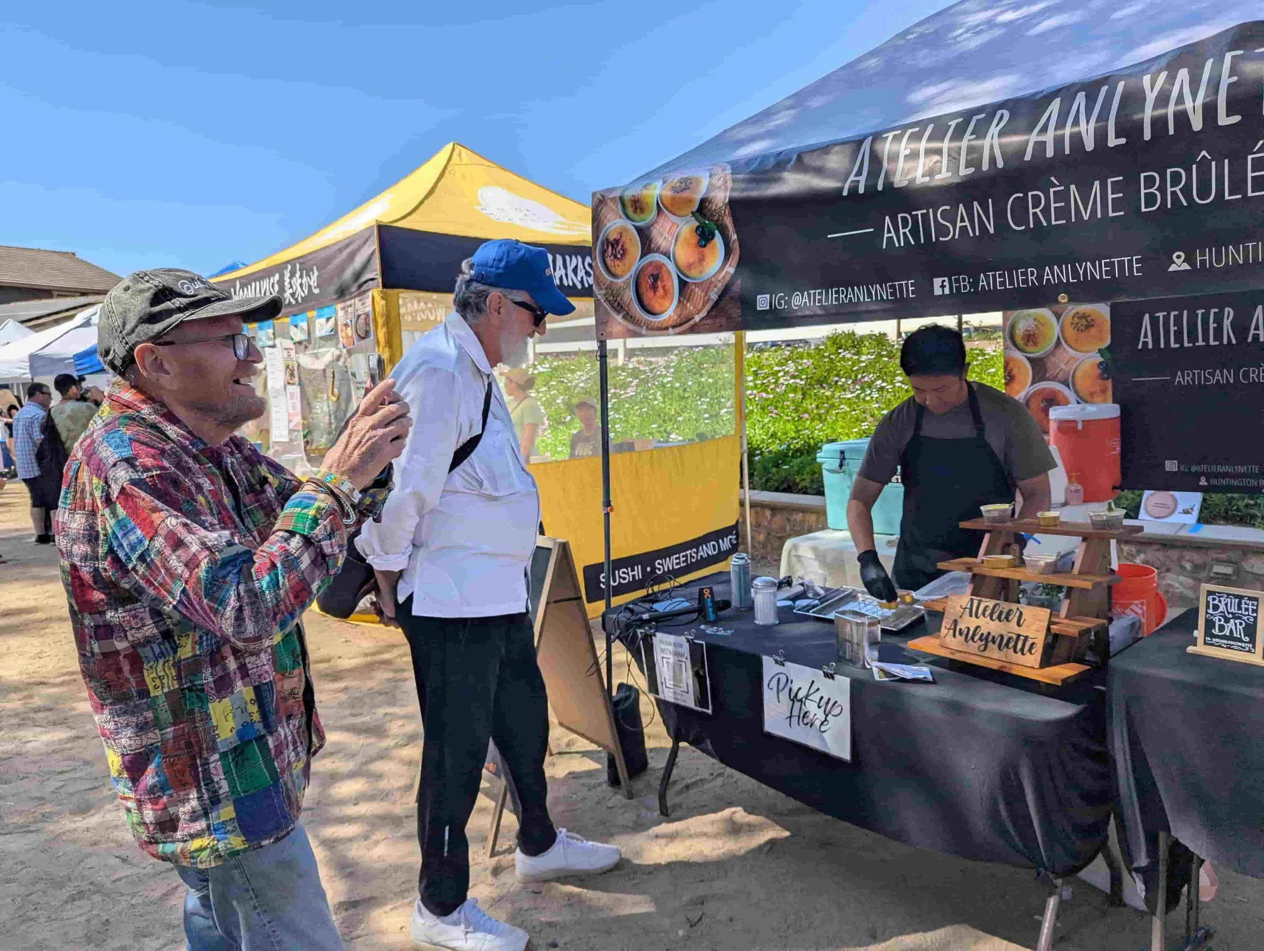 Customers watching a live crème brûlée dessert station by Atelier Anlynette at an outdoor market