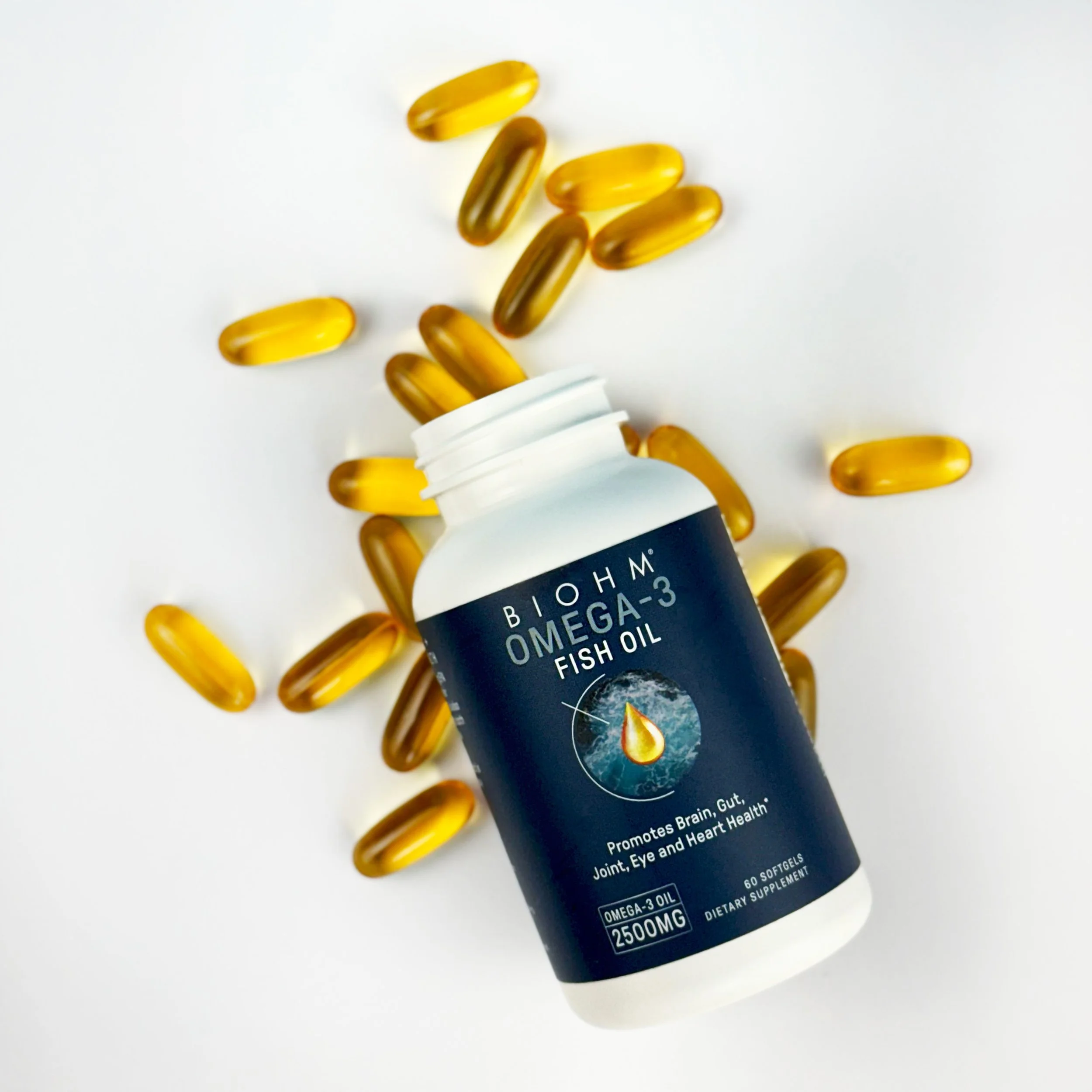 A white bottle of dietary supplement omega-3 fish oil capsules with a black and white label, surrounded by several yellow gel capsules on a white background.