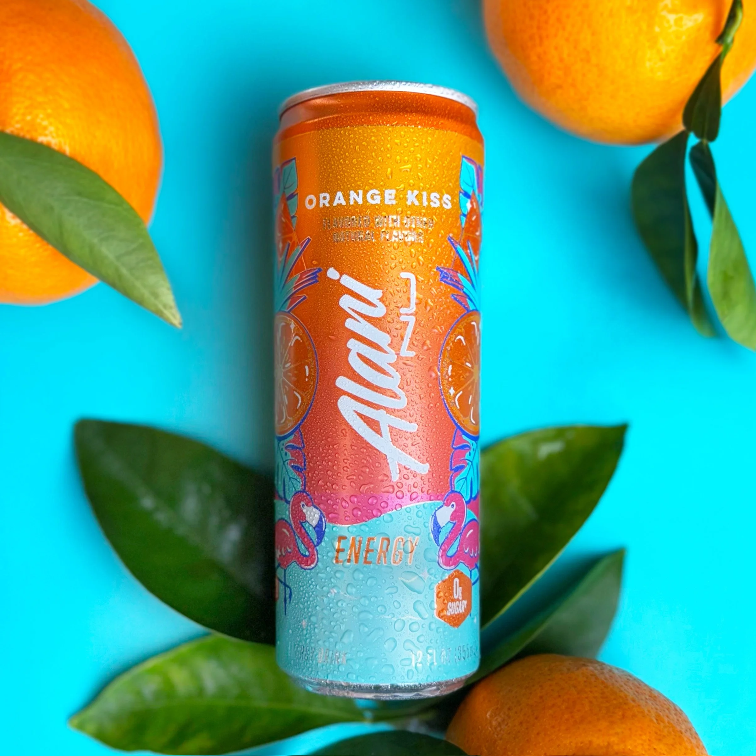 Close-up of an energy drink can labeled 'Orange Kiss' surrounded by oranges and green leaves on a turquoise background.