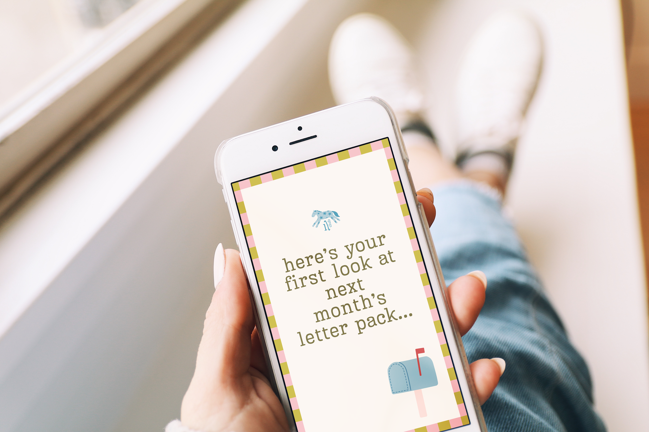 Person holding a smartphone with a colorful border, displaying a newsletter with a blue pony logo and text about a letter pack.