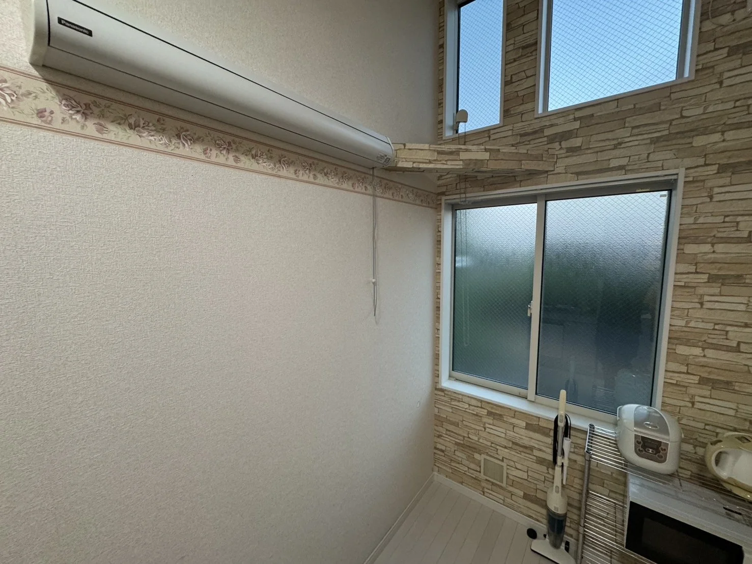 窓のある部屋の interior with vacuum cleaner, microwave, and cooking utensils