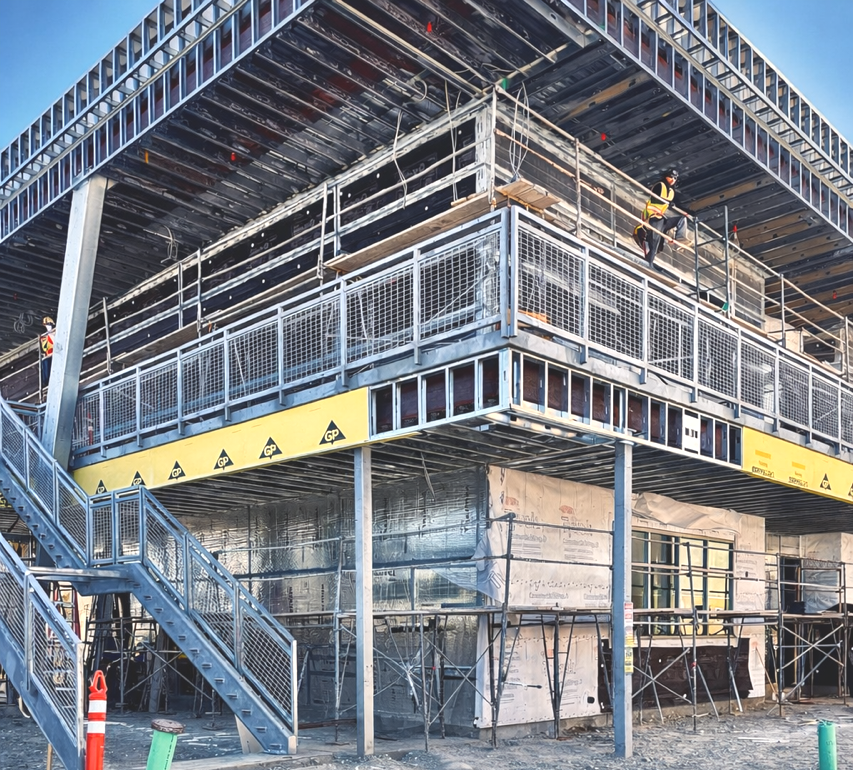 Construction workers on scaffolding and elevated platforms working on a multi-story building under construction.